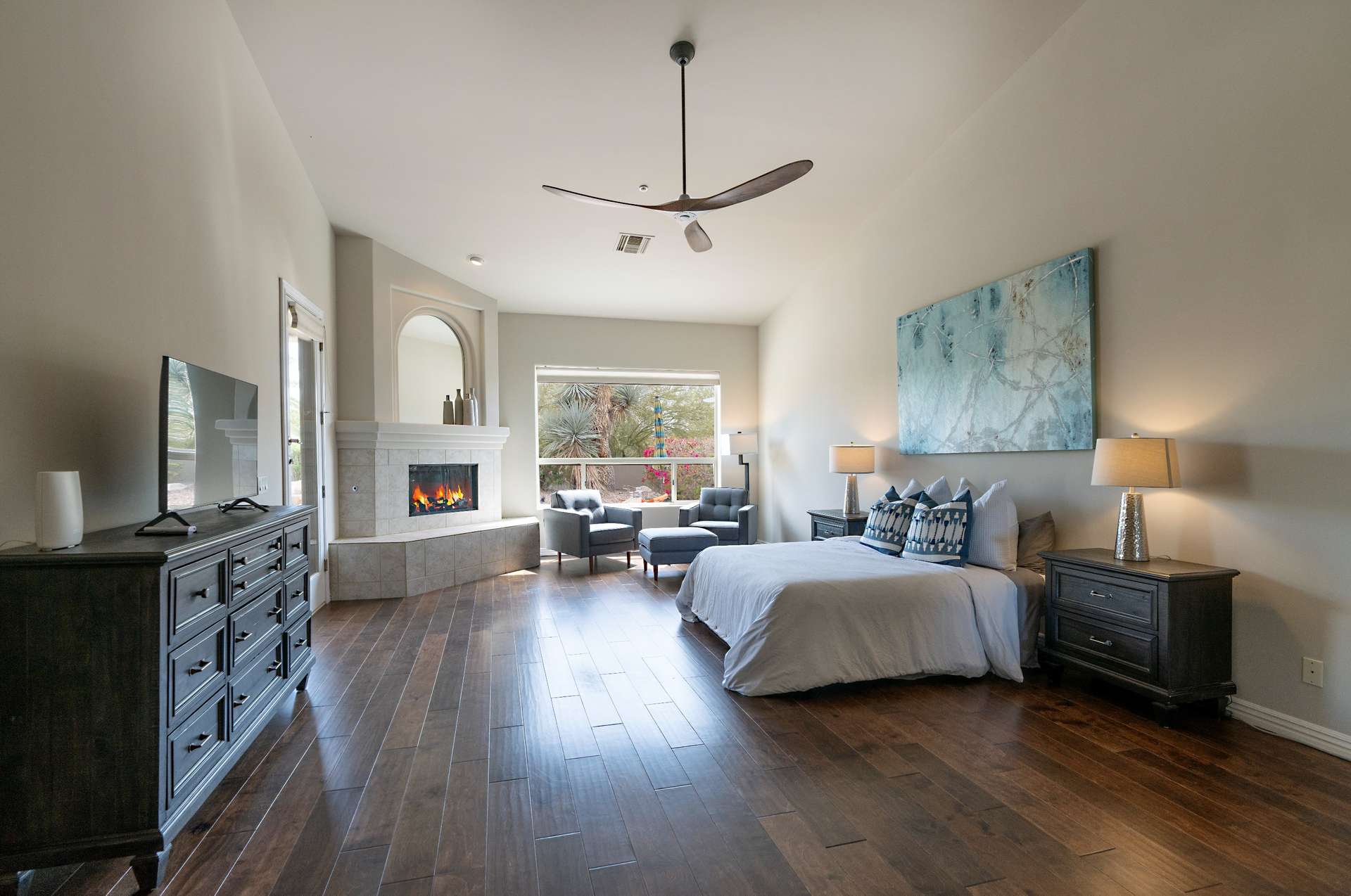 14 of 65. The oversized primary suite features a cozy fireplace, seating area, and rich hardwood floors. Large windows frame desert views, offering both elegance and comfort in this Scottsdale home.