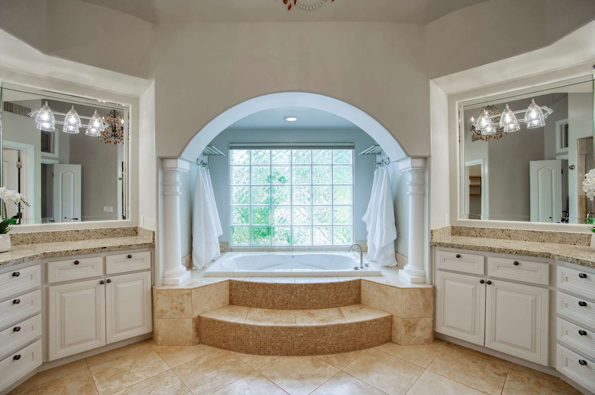 16 of 65. A spa-like experience awaits in this elegant bathroom featuring a soaking tub framed by columns and a glass block window. Relaxation and luxury meet in the heart of Scottsdale.