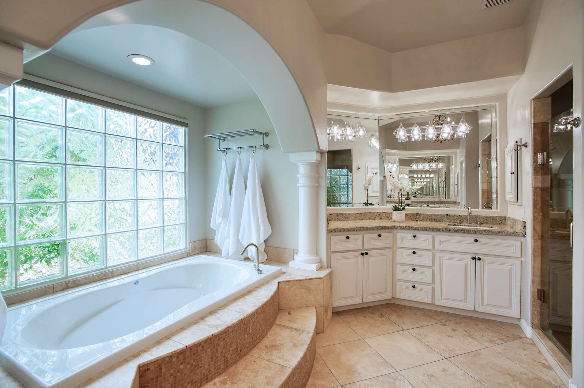 17 of 65. This refined bathroom includes two expansive vanities, a walk-in shower, and stunning tilework under a tray ceiling all wrapped in a soft, spa-inspired color palette.