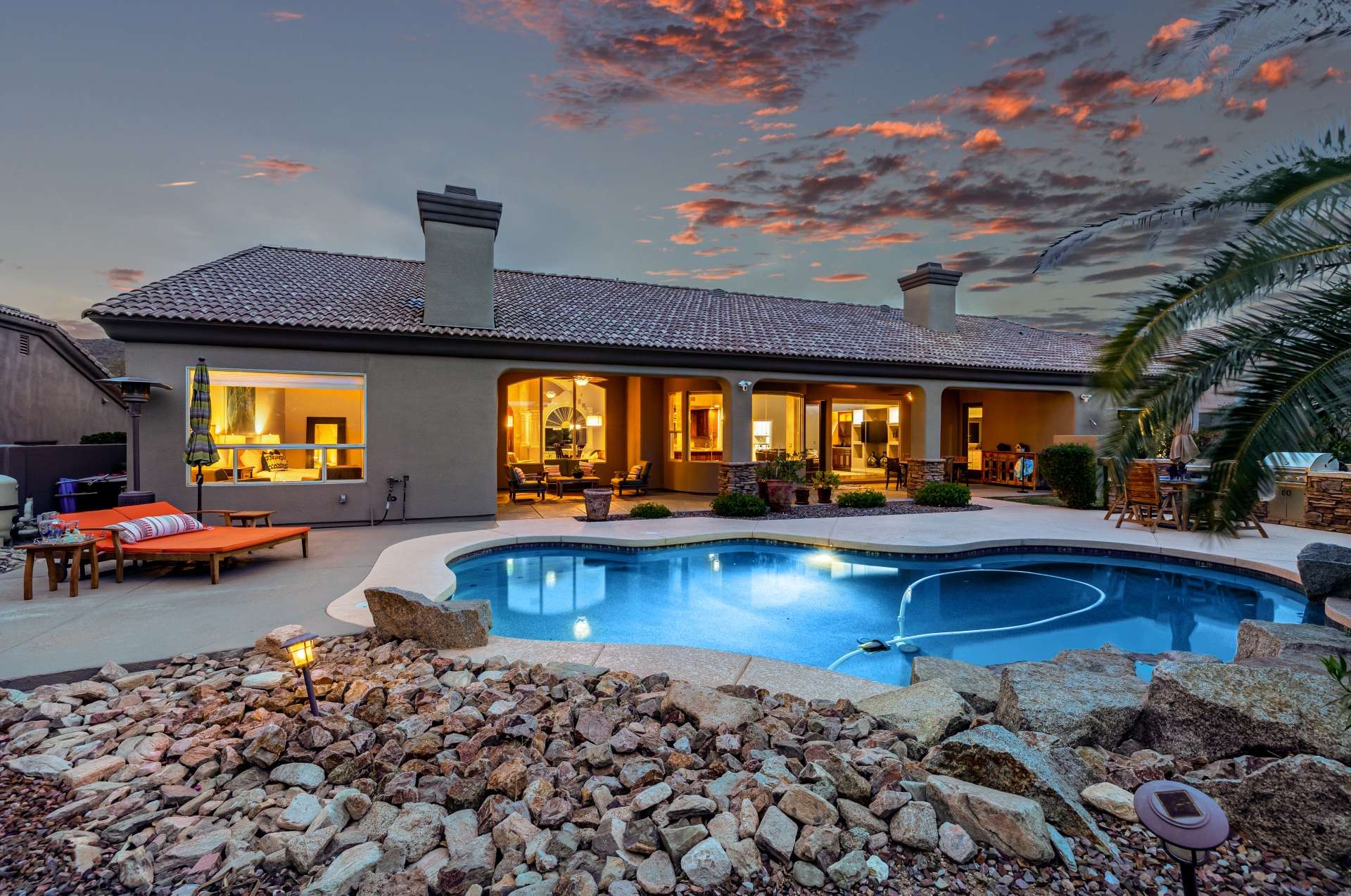 42 of 65. Featuring a gorgeous covered patio with architectural columns and soft ambient lighting, this backyard sets the tone for effortless entertaining. The pebble-finish pool and desert landscape offer a relaxing, energy-efficient escape.