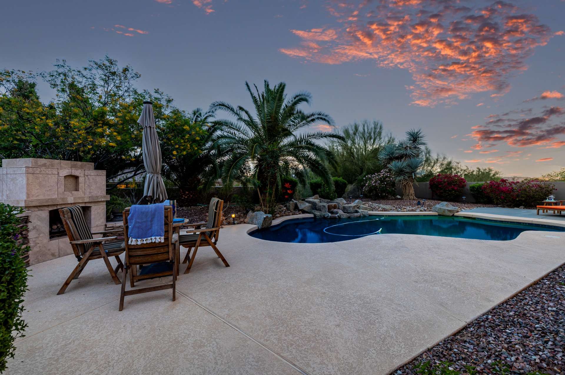 43 of 65. This inviting outdoor dining space is nestled beside a built-in fireplace, creating a cozy desert atmosphere. Surrounded by lush foliage and expansive patio space, it s perfect for evening meals or weekend entertaining.