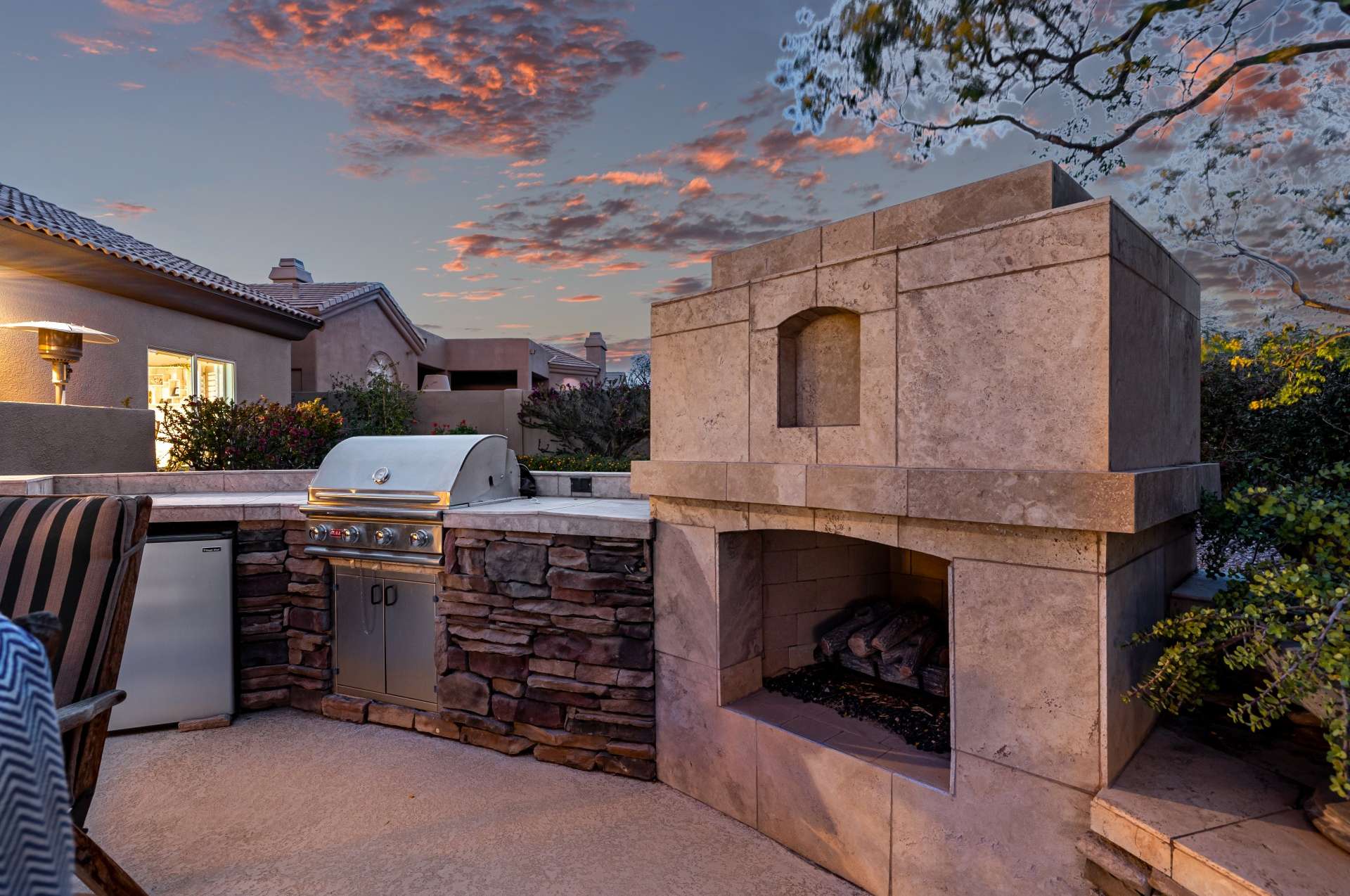 45 of 65. Gather around this luxurious built-in fireplace and BBQ under a sky painted in sunset hues. The stonework and thoughtful layout add warmth and sophistication to this elevated outdoor living experience.