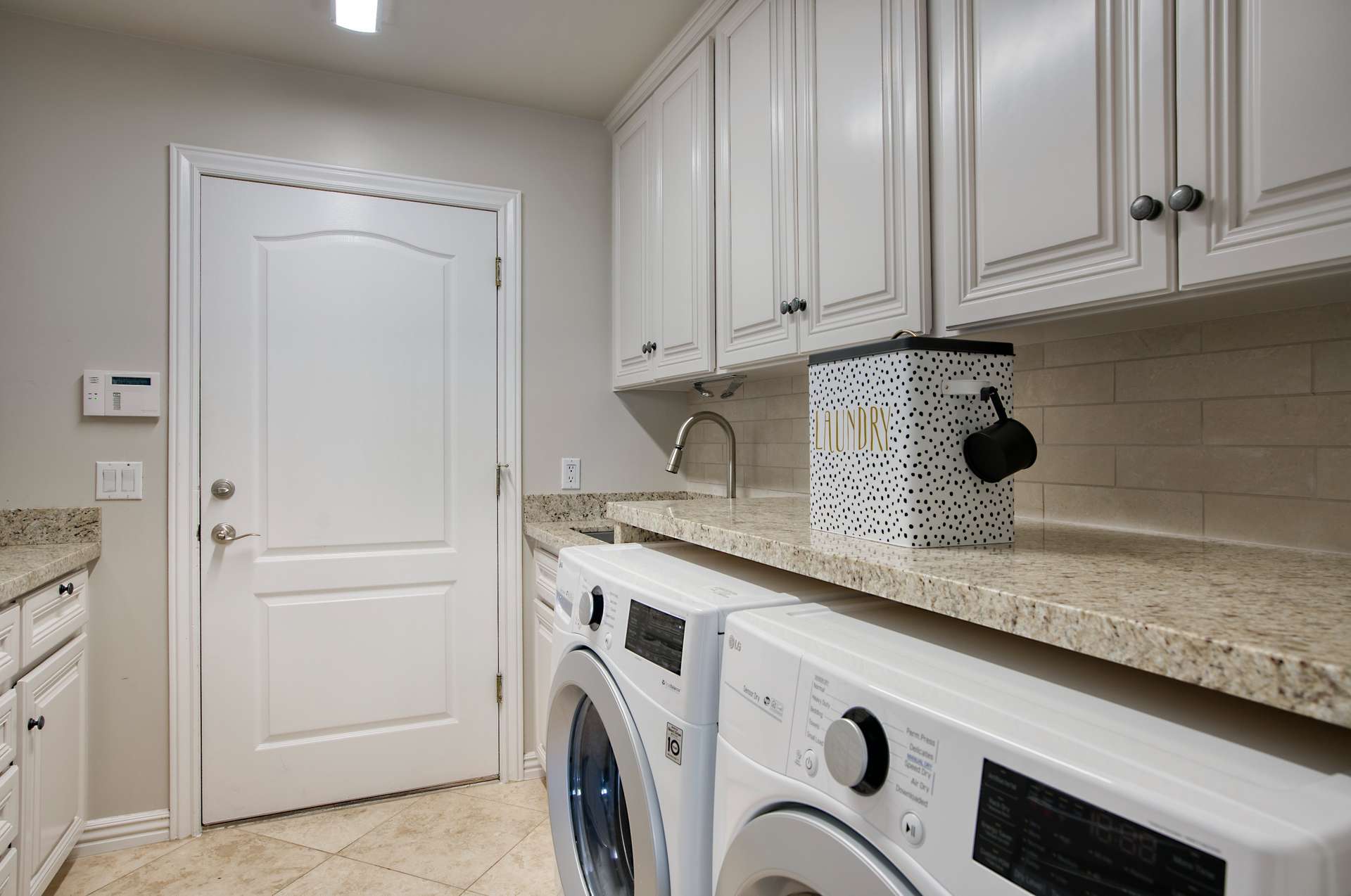 54 of 65. This freshly updated laundry room is as practical as it is polished, featuring granite countertops, abundant cabinetry, and modern LG appliances. Bright, clean, and functional this space makes daily chores a breeze.