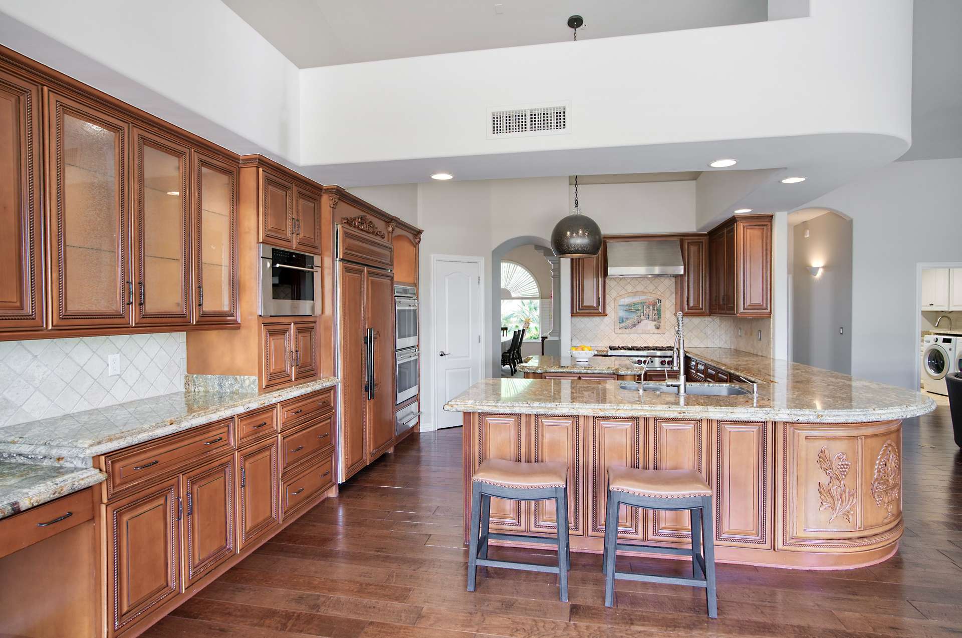 56 of 65. Designed for the culinary enthusiast, this spacious kitchen features premium wood cabinetry, granite counters, and a grand island with bar seating. A cabinet painting allowance invites you to add your personal touch to this elegant space.