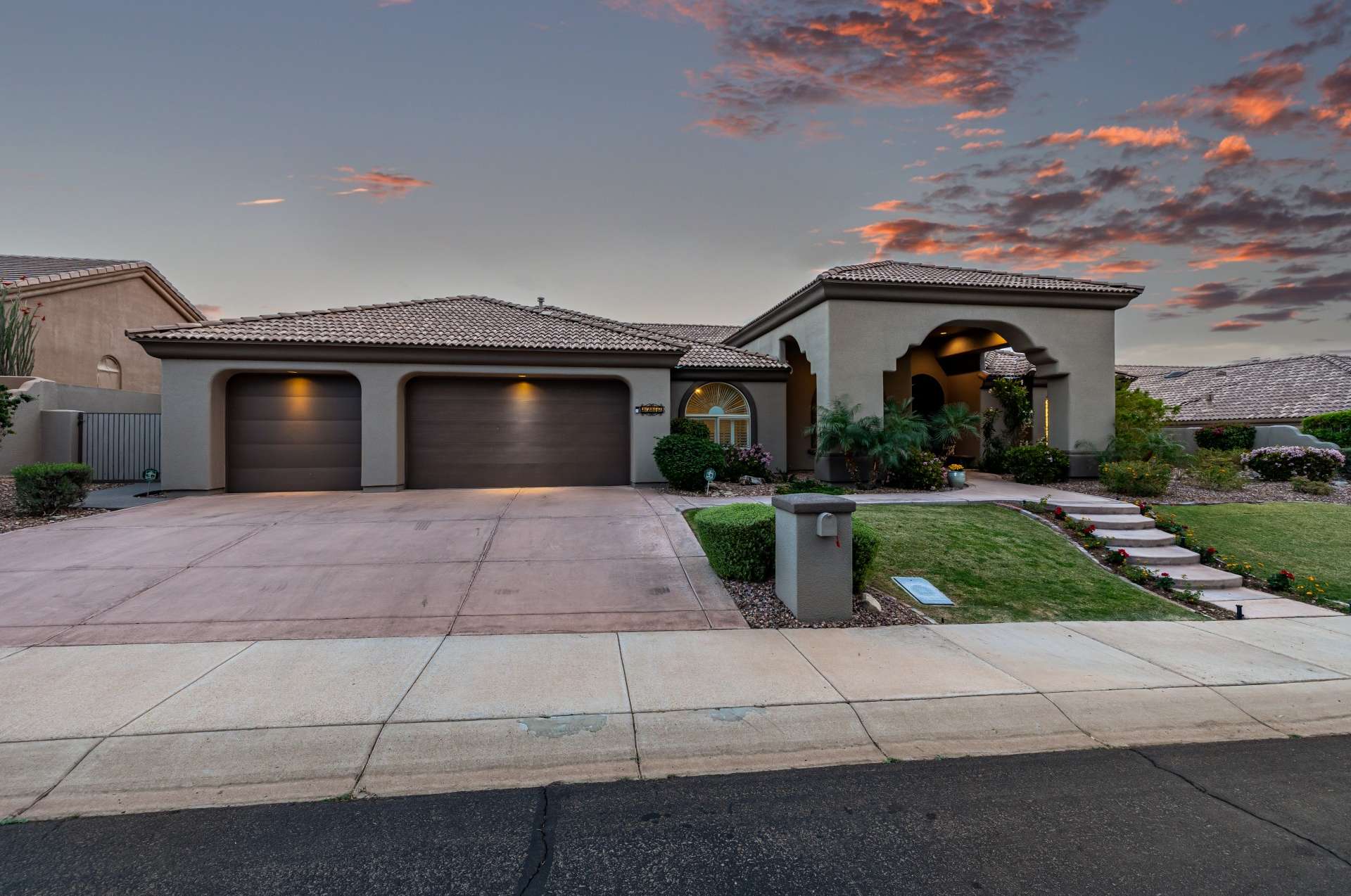 58 of 65. The beautifully landscaped entryway glows beneath a painted sky. This front elevation offers a perfect mix of warmth, privacy, and desert elegance ideal for buyers looking for serene Arizona living.
