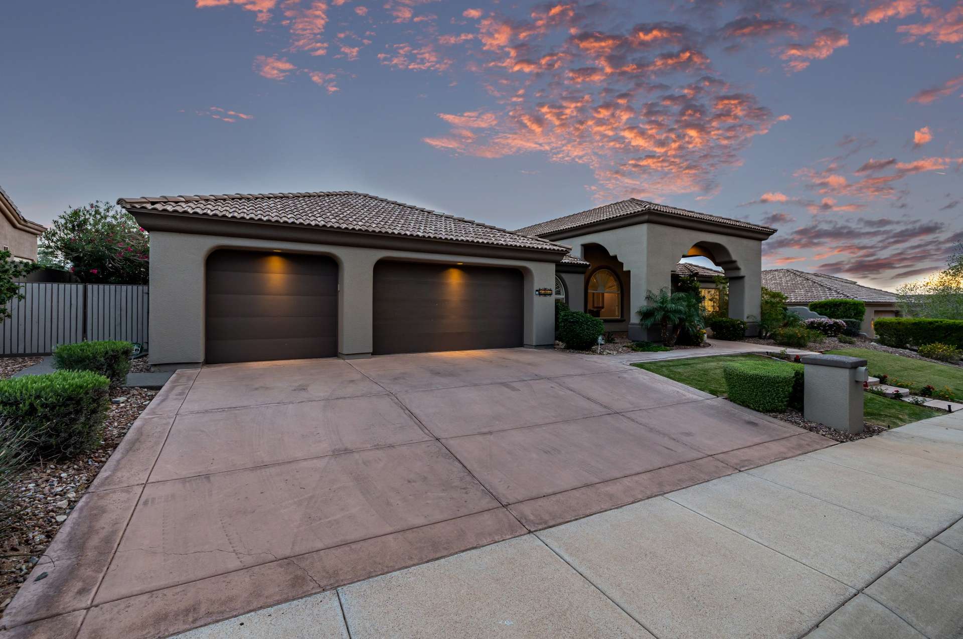 59 of 65. As dusk falls, this home's architectural lines and soft outdoor lighting create an inviting atmosphere. The curved entry path and lush greenery add charm to this well-appointed exterior.