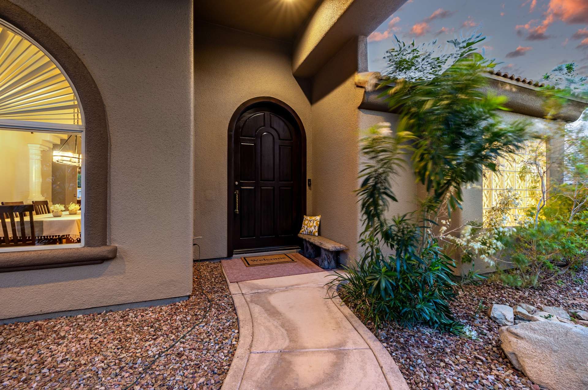 62 of 65. Enjoy Arizona evenings under the shaded entryway of this stylish home. A curved path, potted plants, and subtle lighting combine to create a warm, welcoming feel for residents and visitors alike.