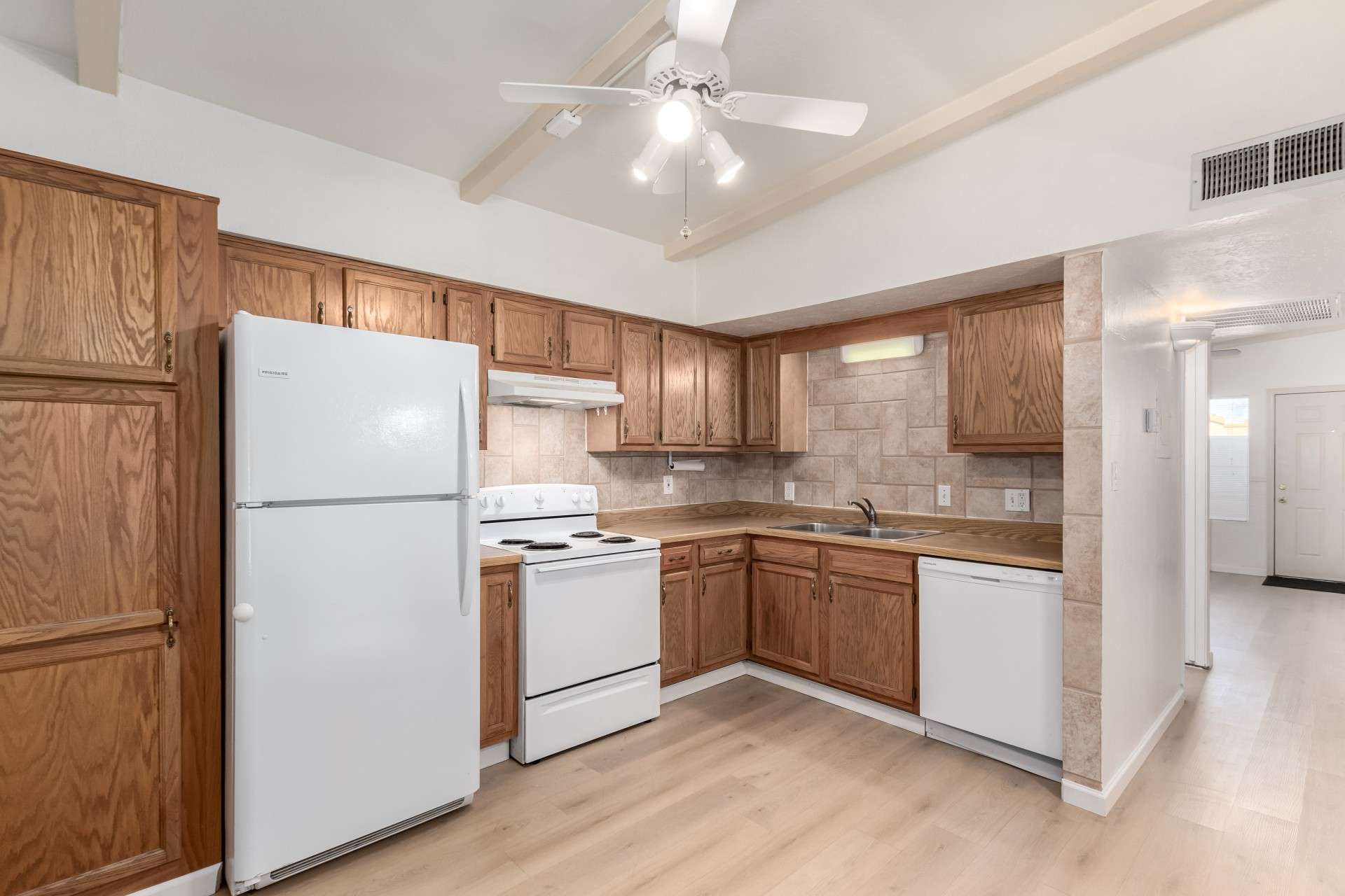 7 of 26. This well-lit kitchen features classic wood cabinetry, tiled backsplash, and abundant storage. With a functional layout and updated flooring, this space is perfect for meal prep and casual dining. Located in a prime Phoenix location near shopping, dining, and entertainment.