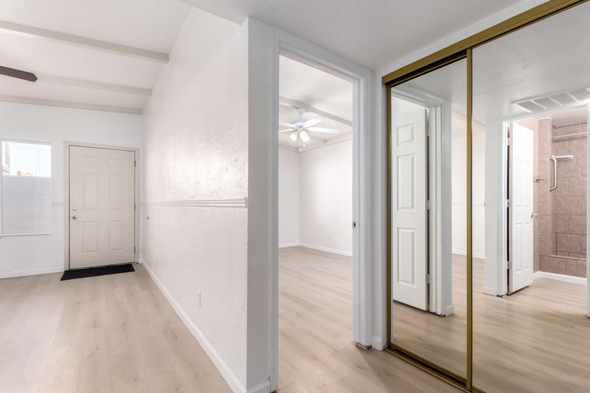 5 of 26. The spacious hallway is enhanced by floor-to-ceiling mirrored closet doors, giving an expansive feel while offering ample storage. The updated flooring and neutral tones provide a modern touch in this centrally located Phoenix condo.