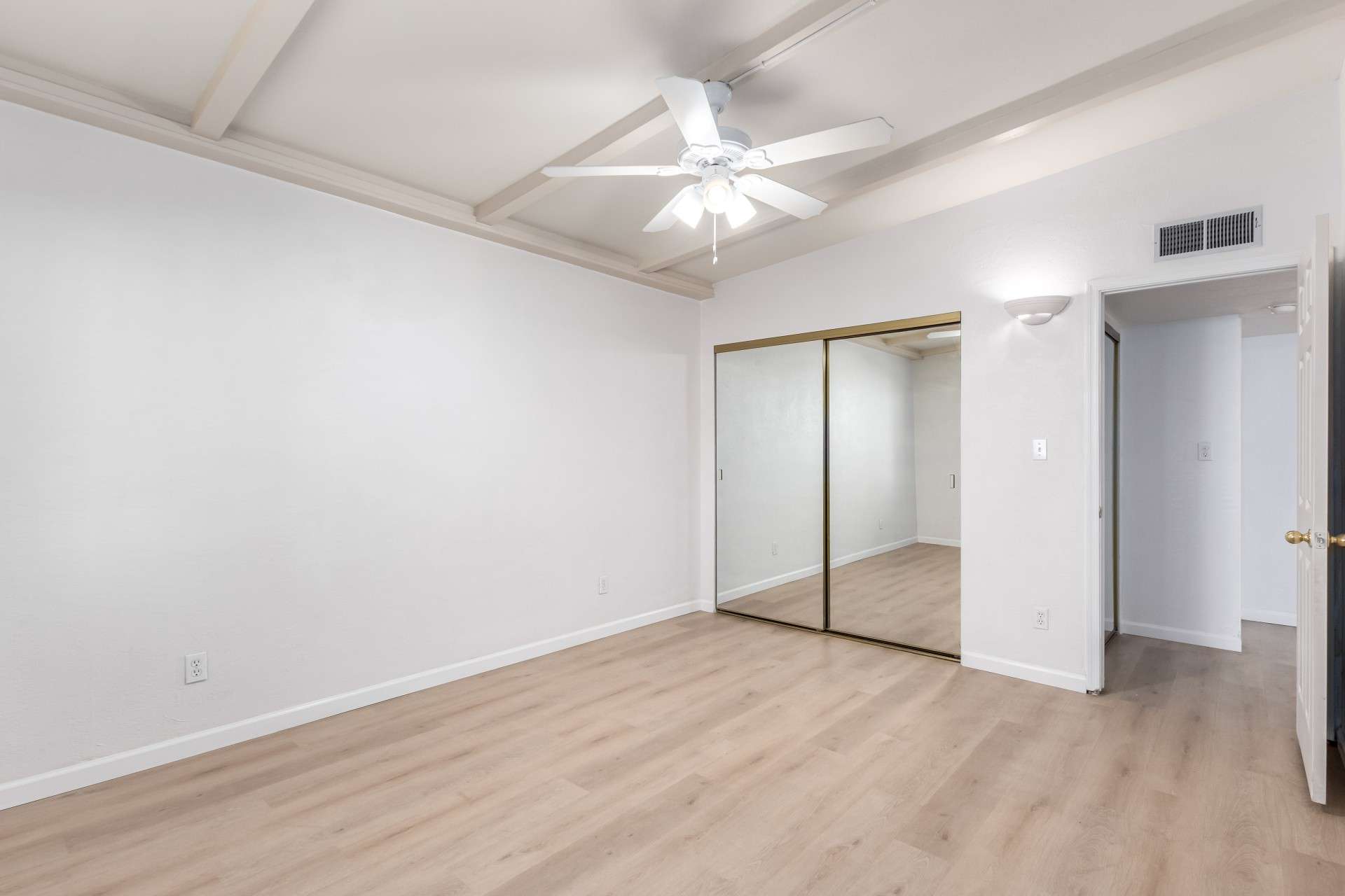 15 of 26. The spacious primary bedroom boasts mirrored closet doors, neutral tones, and updated flooring. A large window allows natural light to brighten the space, making it a cozy and welcoming retreat in this move-in-ready condo.