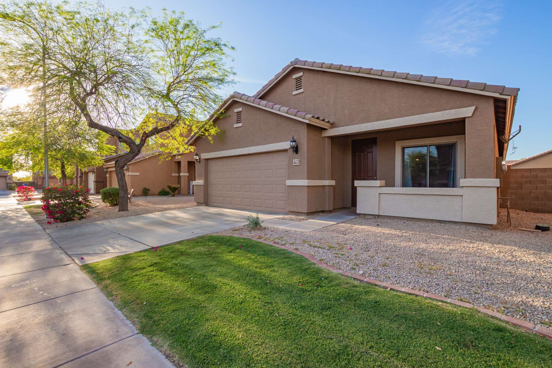 32 of 37. Green grass and rock landscaping bring balanced beauty to the front yard. With north/south orientation and shaded patio features, the home is designed for comfort in the Arizona heat.
