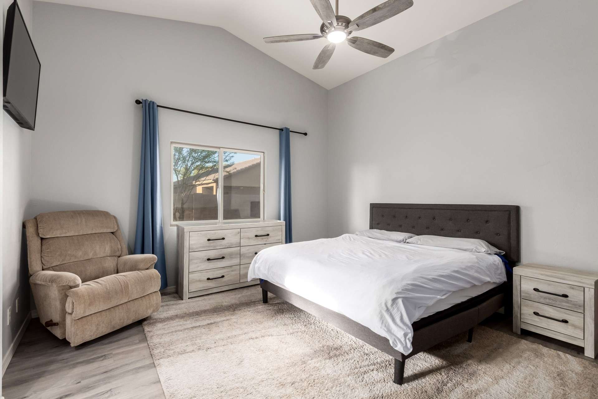 4 of 37. Vaulted ceilings and plush carpet create a cozy, elevated feel in this spacious primary bedroom. Ample natural light flows in through the window, creating a soothing and serene retreat in this Laveen home.