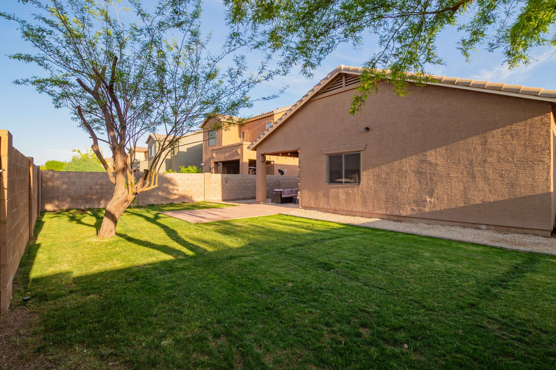 34 of 37. Natural light and soft shade define this serene backyard setting, complete with privacy block fencing and a generous lawn space. Enjoy the Arizona lifestyle in a backyard designed for both play and relaxation.