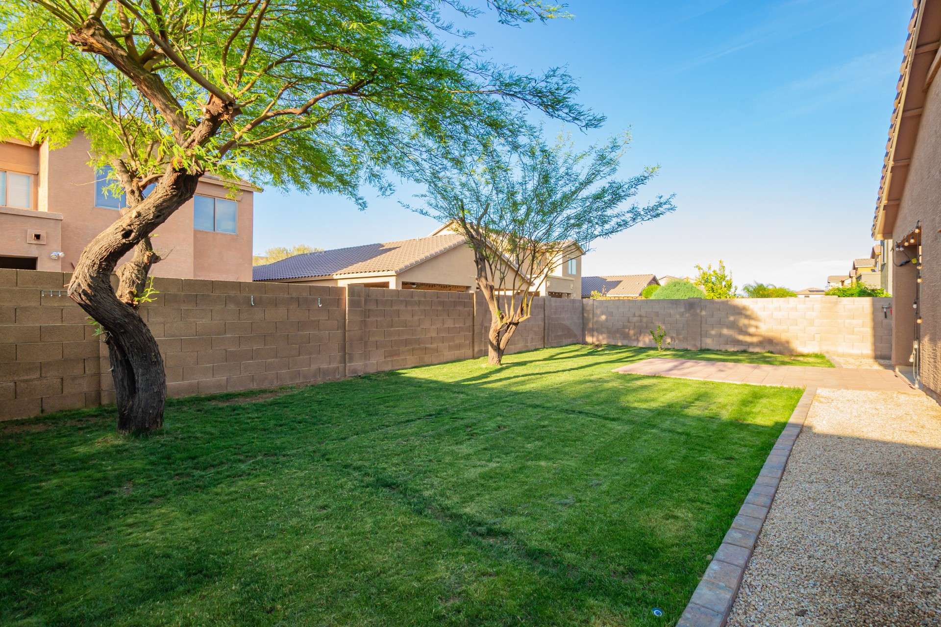 36 of 37. This inviting green yard includes mature desert trees, low-maintenance gravel paths, and expansive lawn space great for kids, pets, or weekend gardening. Enjoy the privacy and tranquility of this secure, walled backyard.