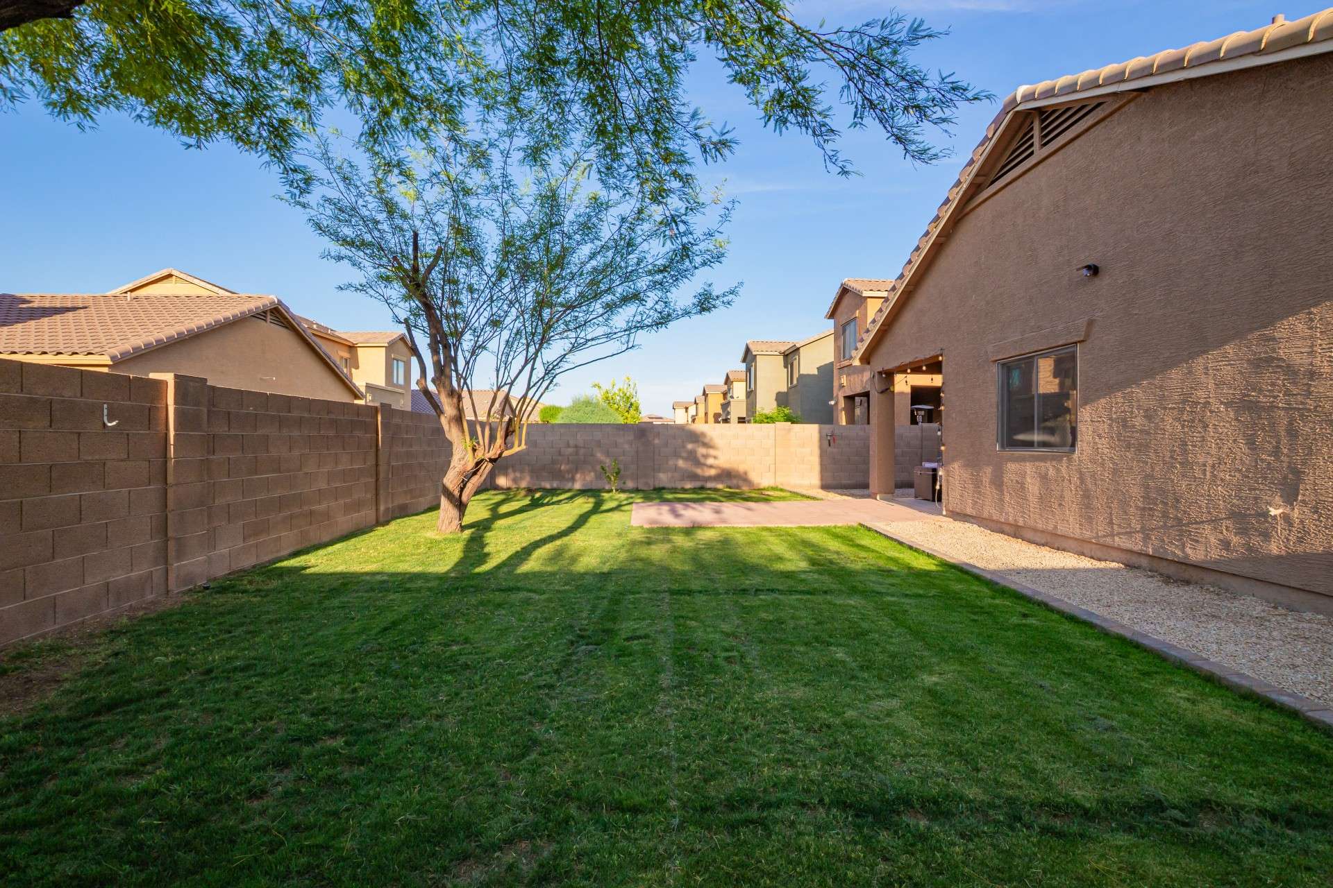 37 of 37. A broad view of the backyard reveals a well-maintained green lawn, framed by privacy fencing and shaded by tall trees. This outdoor area provides plenty of room for recreation, entertaining, or enjoying peaceful evenings under the stars.