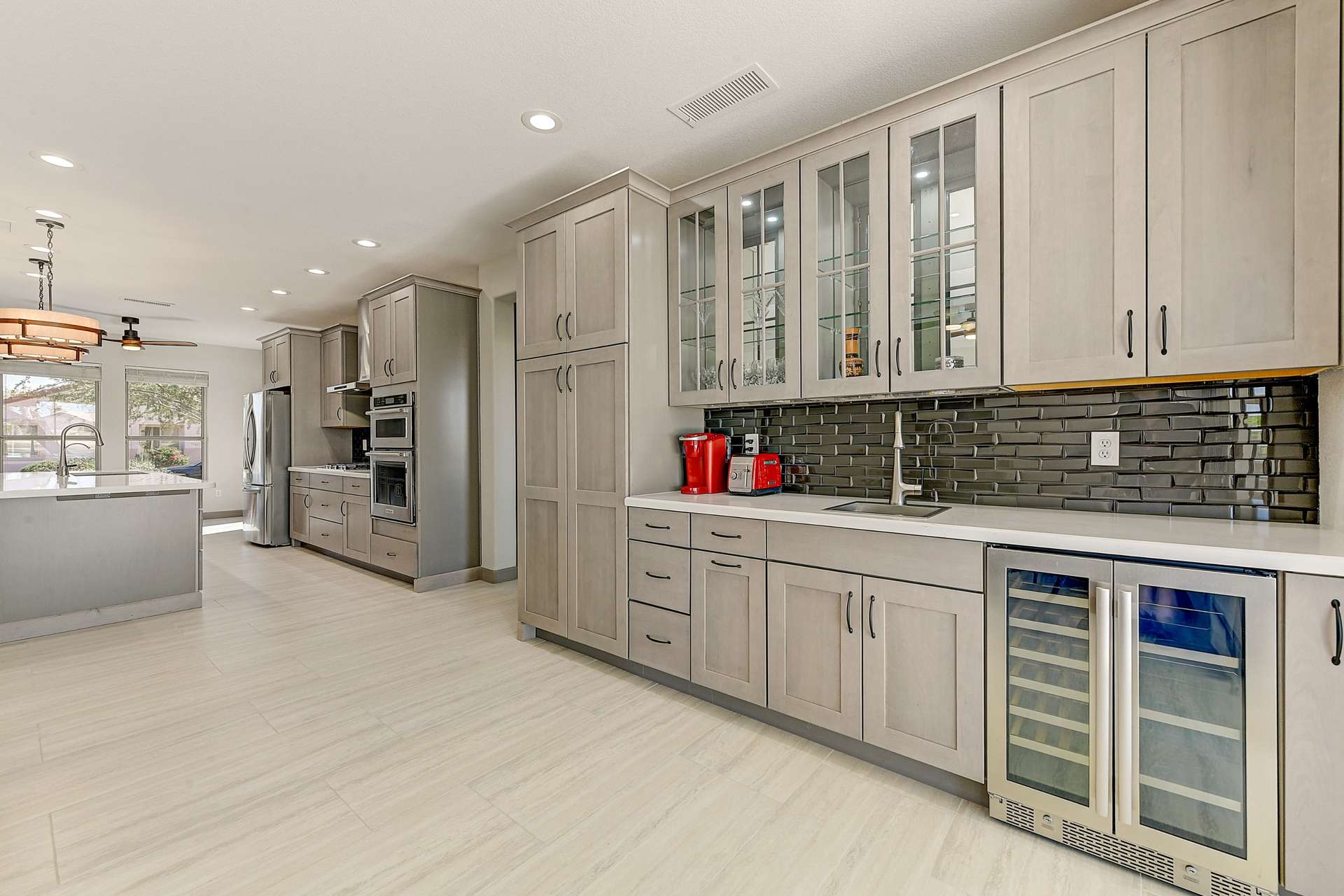 11 of 35. A stunning built-in cabinetry wall combines form and function with elegant glass-front cabinets, deep drawers, and a wine fridge below. Ideal for hosting in style or storing your favorite essentials in this upgraded Surprise home.