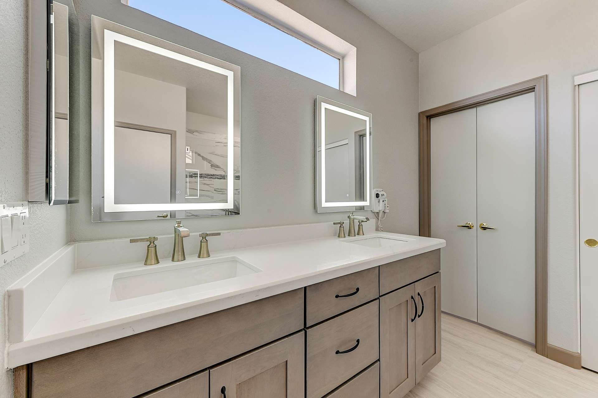 16 of 35. The dual-sink vanity shines with quartz countertops, under-mount sinks, and sleek LED mirrors. Paired with brushed hardware and designer faucets, this space is both elegant and functional.