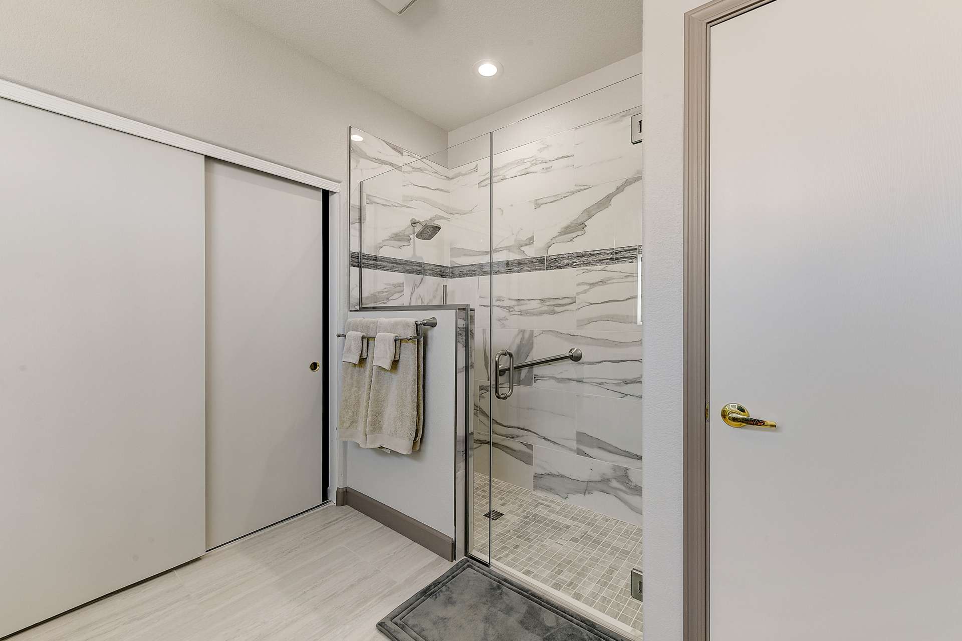 17 of 35. A glass-framed shower with striking tile accents and premium hardware transforms this bathroom into a luxury experience. Every feature, from safety bars to recessed lighting, is built with care and convenience in mind.