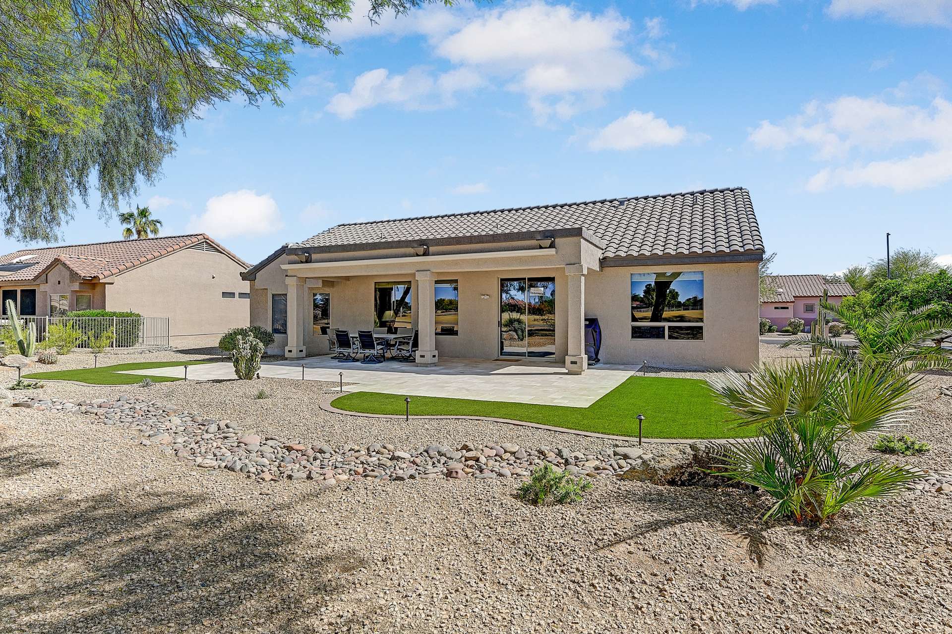 27 of 35. The home s back fa ade blends indoor-outdoor flow with large sliding doors and picture windows. Covered patio, upgraded pavers, and turf invite easy entertaining.