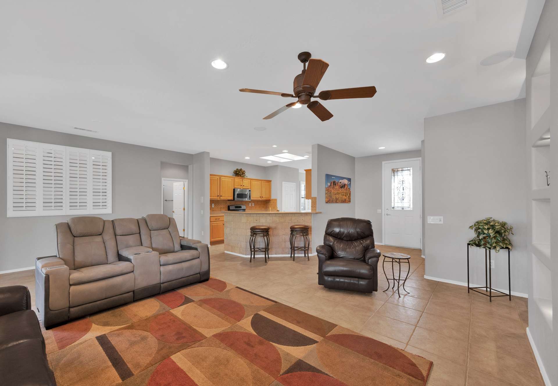 2 of 13. The spacious living room is designed for relaxation with reclining furniture, tile floors, and natural light. Its open-concept flow is ideal for short-term tenants wanting both space and connection.