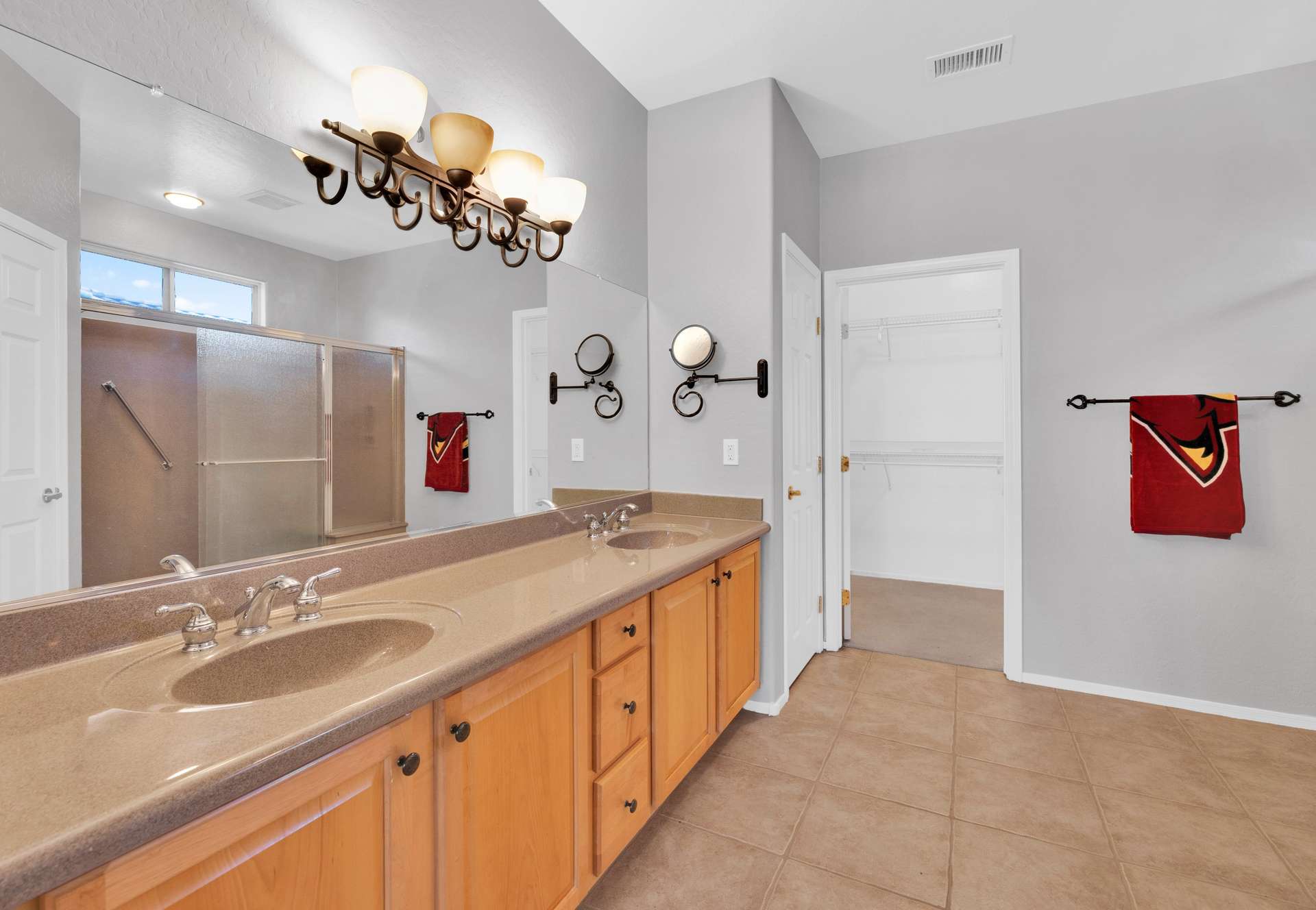 8 of 13. The en-suite bathroom boasts dual sinks, a large mirror, and solid-surface counters offering function and comfort with a polished look for guests and residents alike.