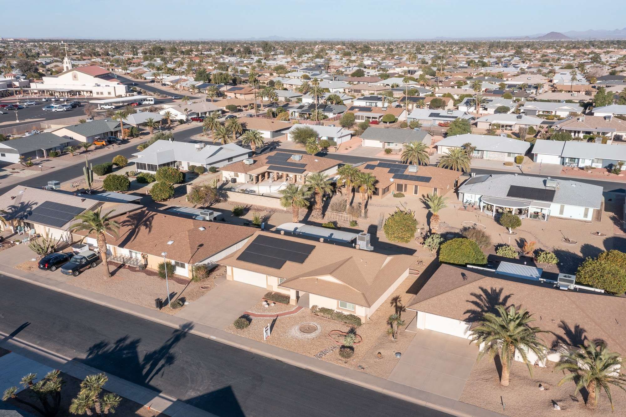 23 of 48. A captivating neighborhood view featuring well-maintained homes surrounded by mature palms and desert plants. This peaceful Sun City West neighborhood offers a picture-perfect backdrop for Arizona living.