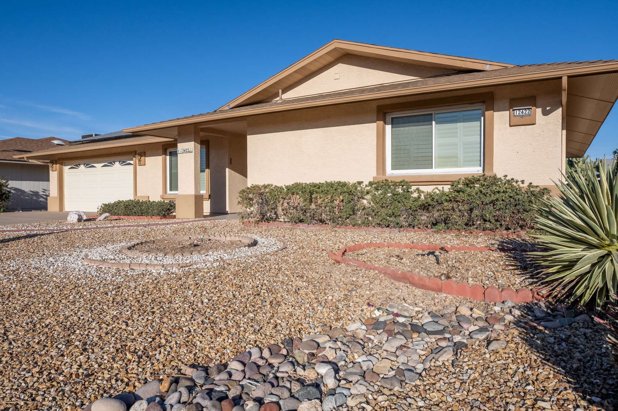 12 of 48. Featuring curb appeal and fully paid solar panels, this property offers energy efficiency and style. A desert landscape with gravel and a red-brick path completes the home's inviting exterior.