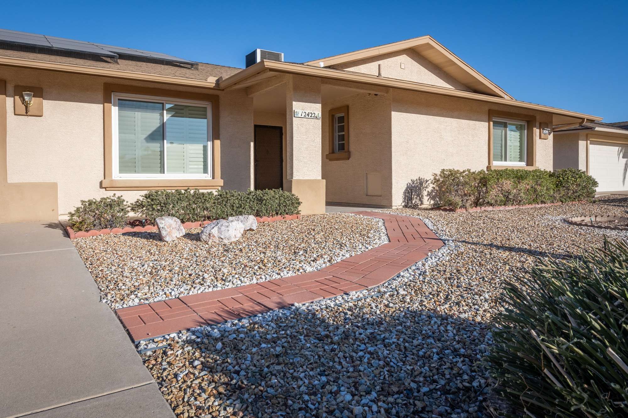 3 of 48. A closer look at the front entryway showcasing modern plantation shutters, a fresh stucco finish, and a thoughtfully landscaped yard, perfect for Arizona's low-maintenance lifestyle.