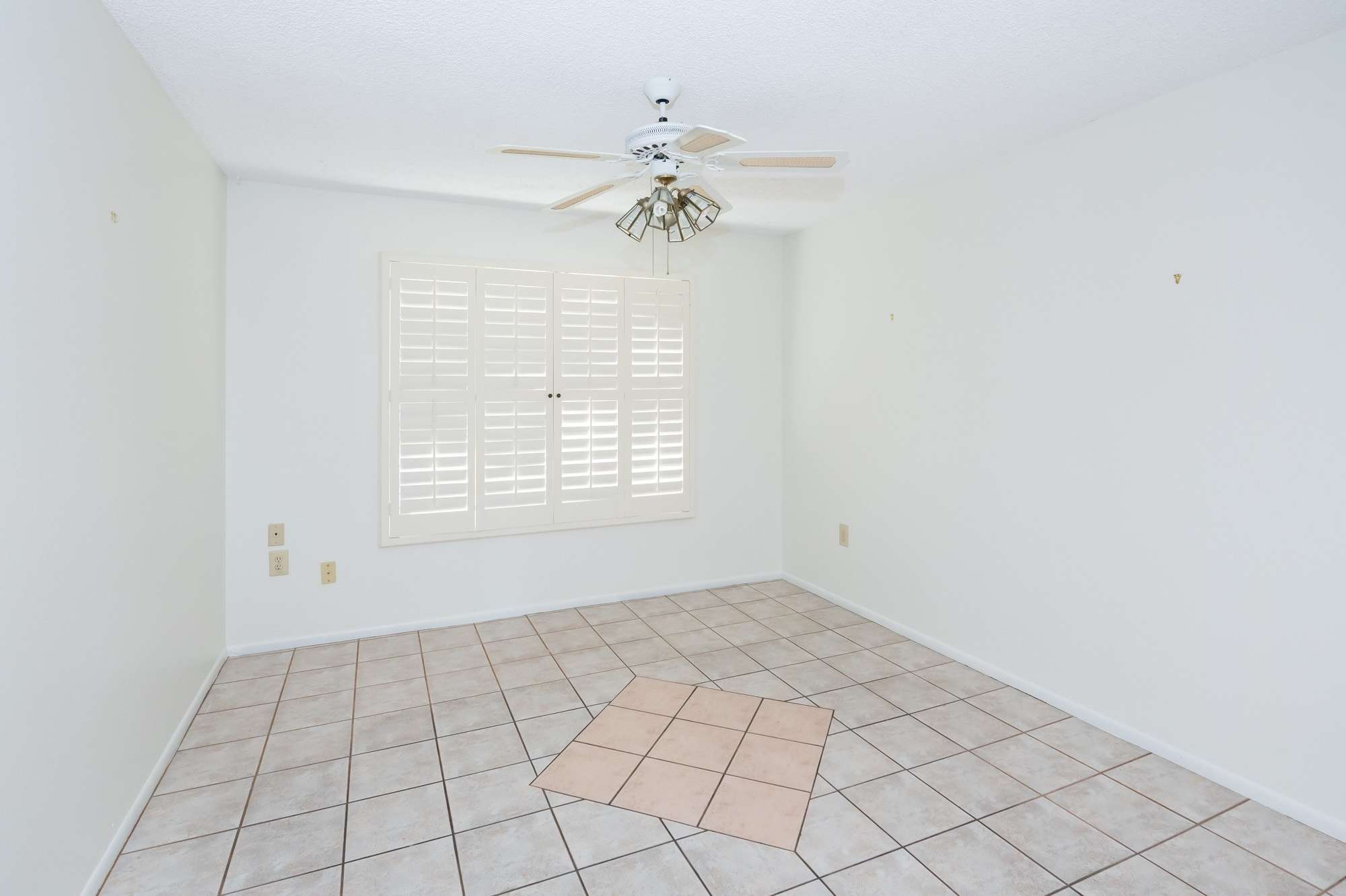 33 of 48. A comfortable living area with a ceiling fan and expansive floor space, providing flexibility for furniture arrangements. The large window offers a serene outdoor view.