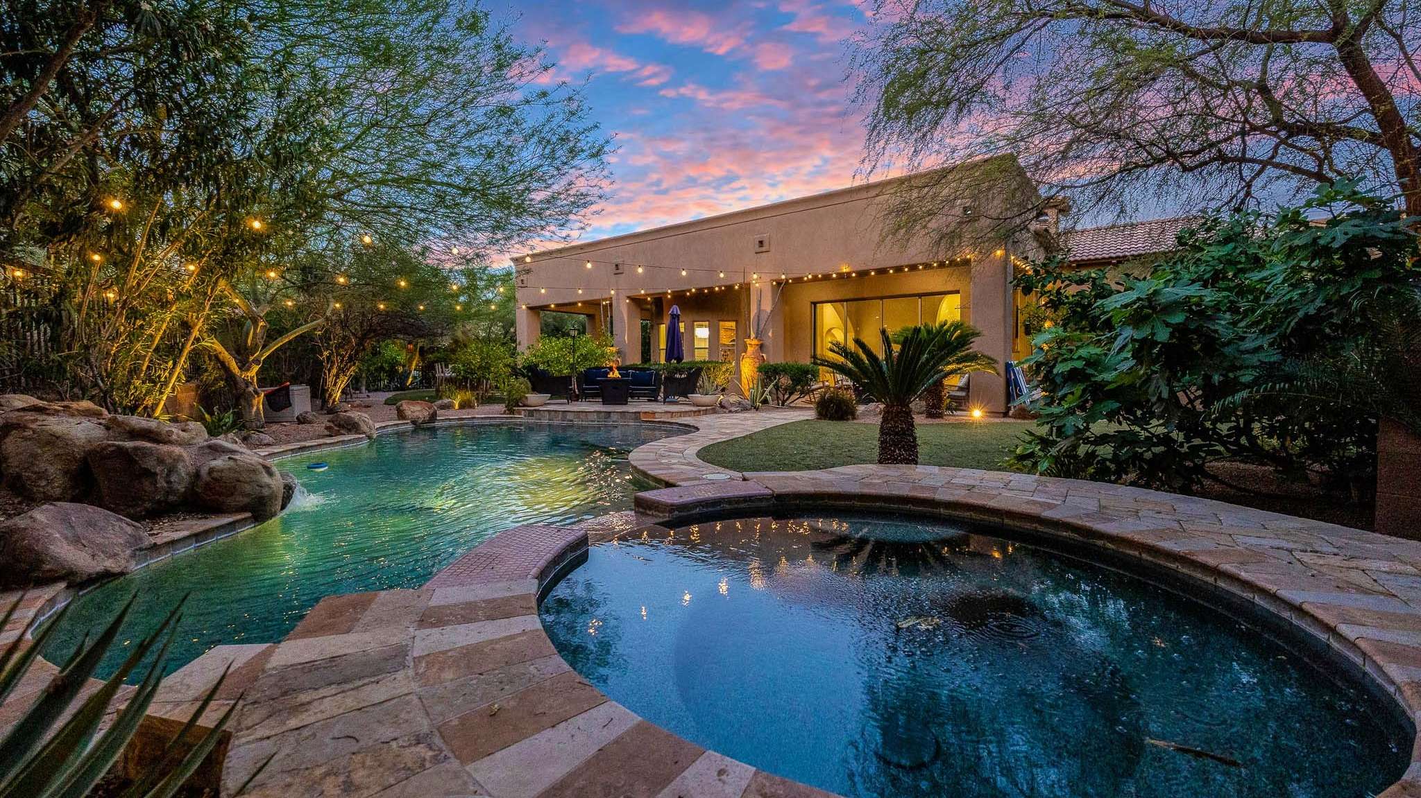 2 of 39. Step into your own Scottsdale resort with this lush backyard featuring a heated pool, raised spa, boulder accents, and string lights. Ideal for serene evenings, family fun, or outdoor entertaining in year-round sunshine.