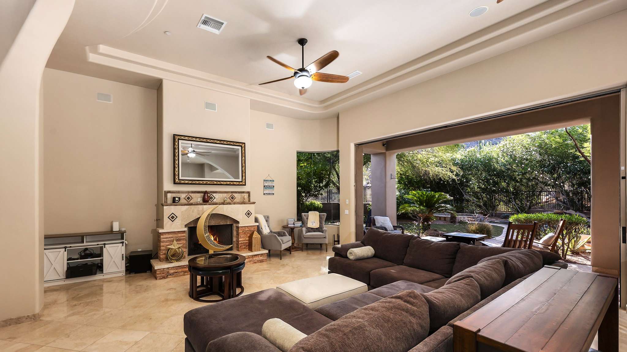 4 of 39. Experience open-concept comfort in this elegant living room, highlighted by large pocket sliders that frame the lush backyard. Tile floors, tray ceilings, and natural light create effortless Scottsdale-style indoor-outdoor living.