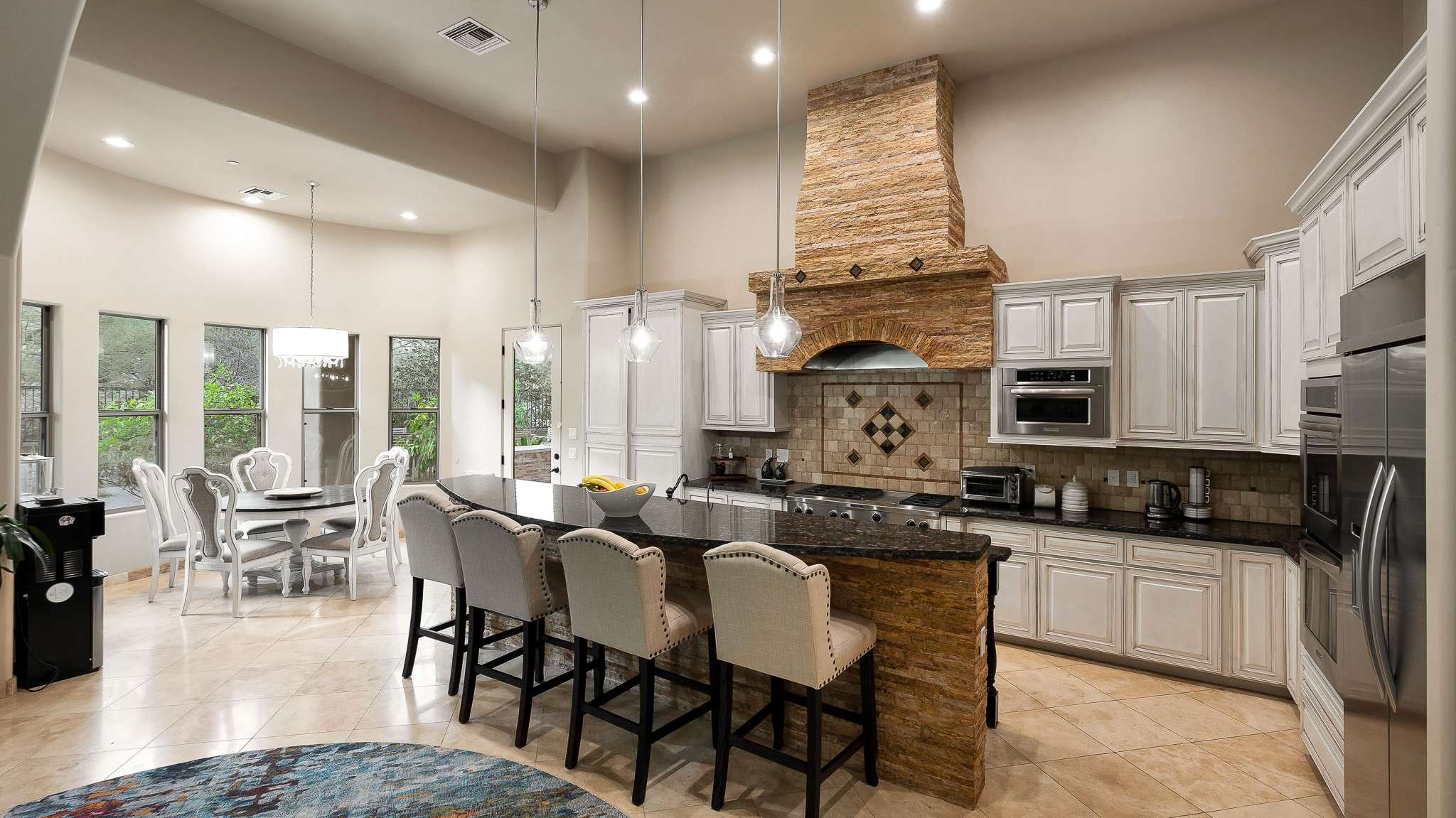 5 of 39. A chef s dream with custom cabinets, granite counters, a statement stone hood, and a cozy dining nook flooded with natural light. This Scottsdale kitchen blends rustic warmth with high-end functionality.