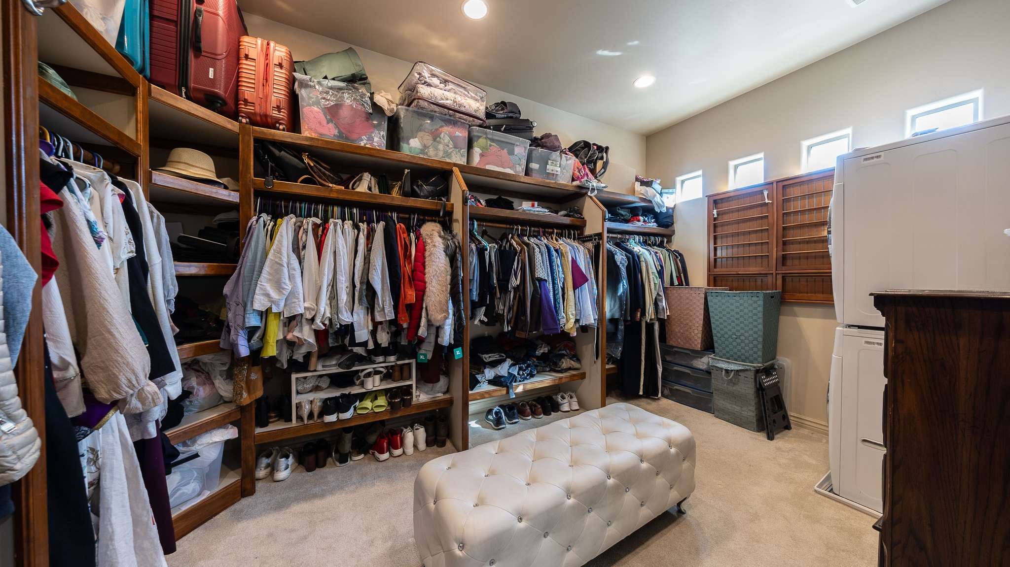 18 of 39. A spacious walk-in closet designed for function and convenience with rich wood shelving, an upholstered bench, and an additional washer/dryer set. Smart living in the heart of Scottsdale.