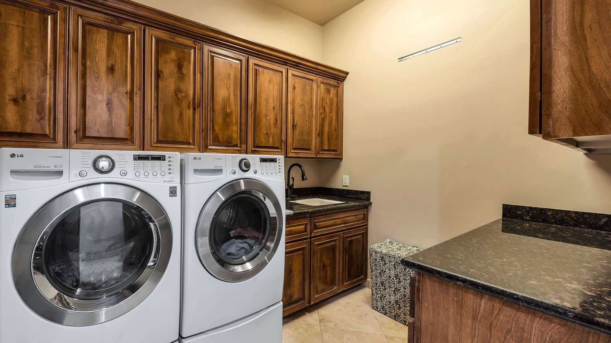 19 of 39. This well-equipped laundry room includes front-load appliances, granite countertops, and plenty of upper and lower cabinetry for storage. A functional and stylish utility space in this upgraded home.
