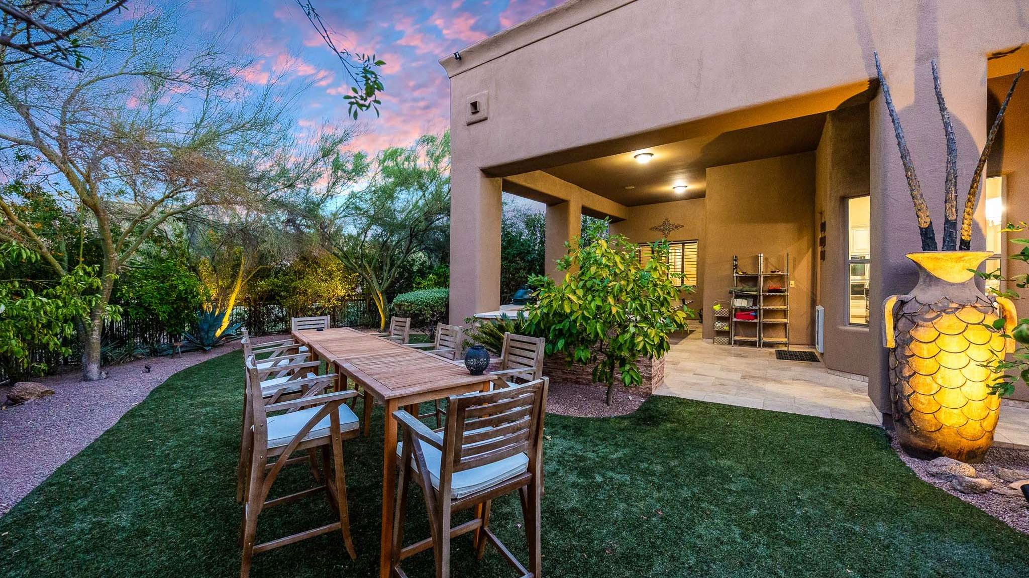 28 of 39. Dine outdoors under the canopy of mature trees in this peaceful backyard space. The extended patio and large dining table make this Scottsdale home perfect for entertaining with ease.