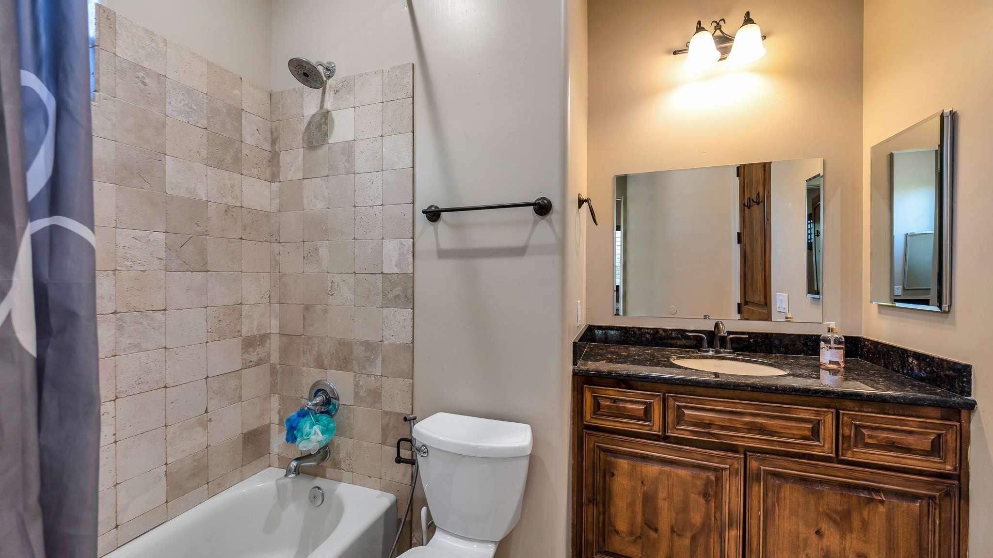 31 of 39. This shared bathroom features rich wood cabinetry, granite countertops, and a tiled shower/tub combo, creating a practical yet elegant solution for connected bedrooms in this spacious Scottsdale home.