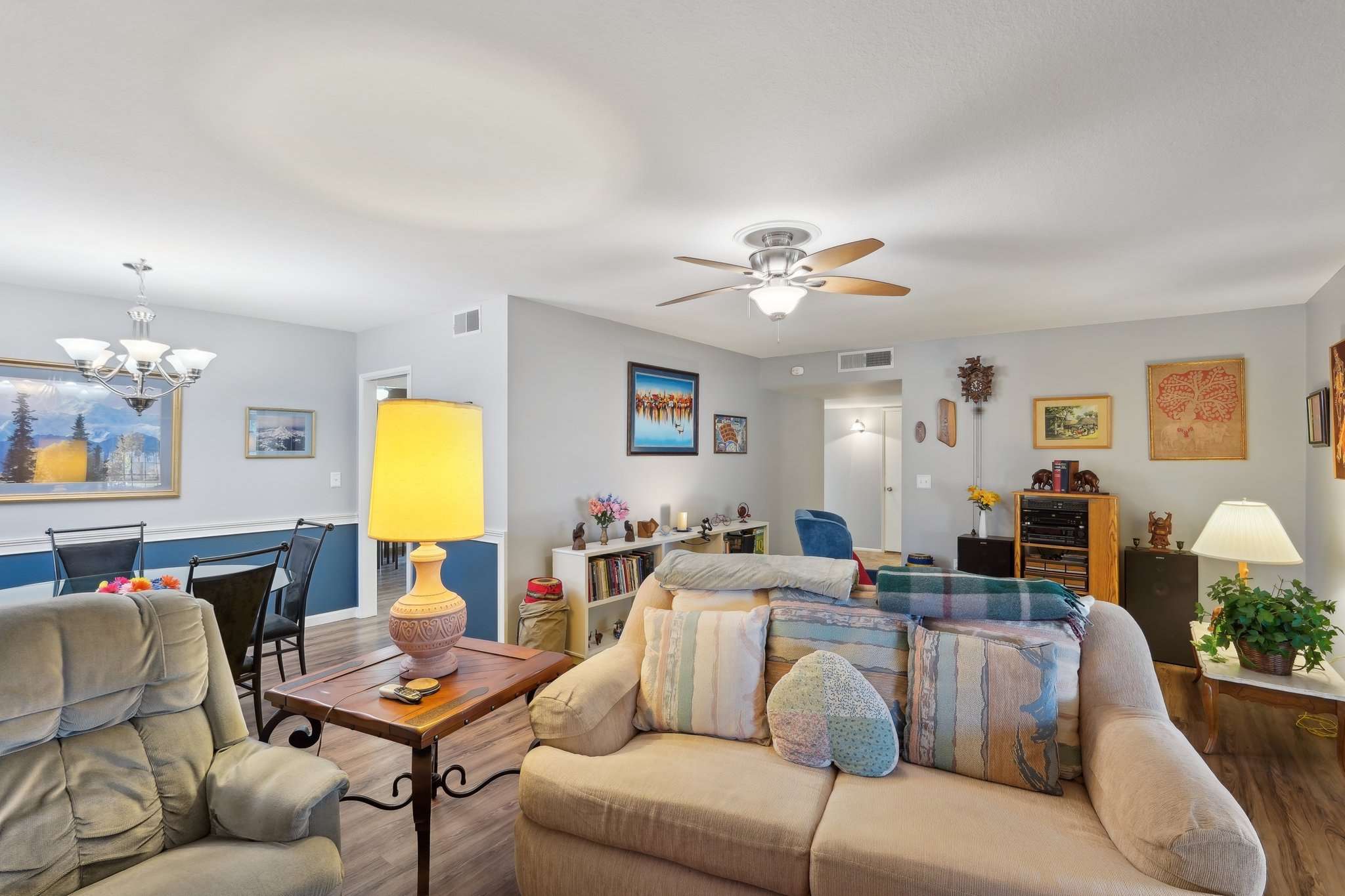 9 of 41. The inviting living room features modern flooring, a ceiling fan, and built-in shelving. The open-concept layout makes this home feel bright and spacious, ideal for entertaining.