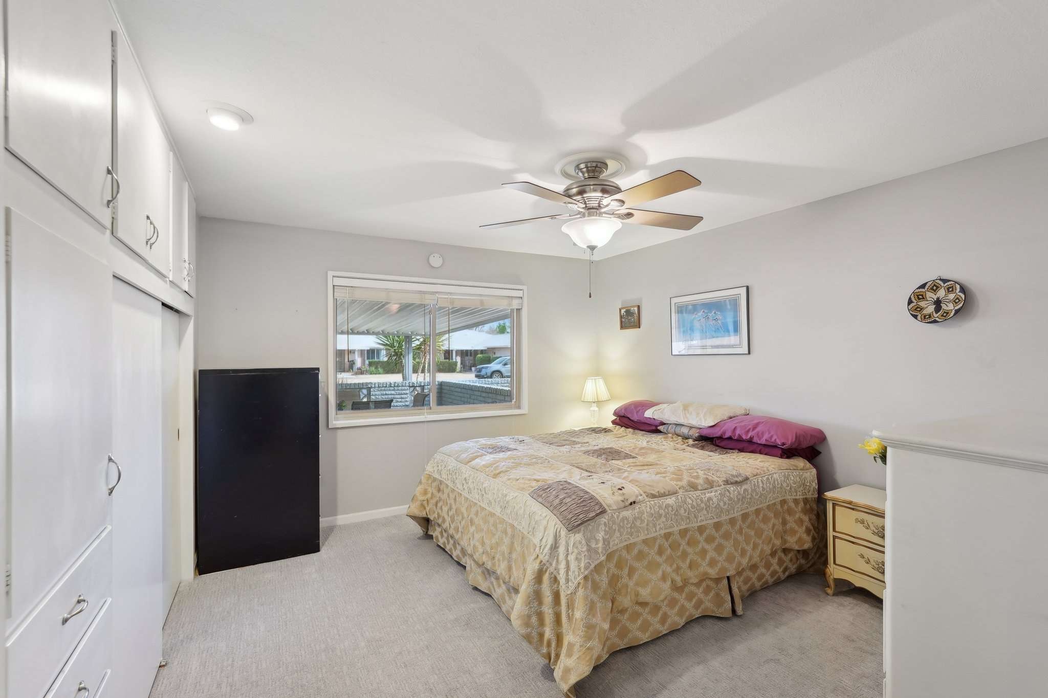 20 of 41. This comfortable bedroom features plush carpet, a ceiling fan, and built-in storage. The large window offers plenty of natural light and a relaxing backyard view.