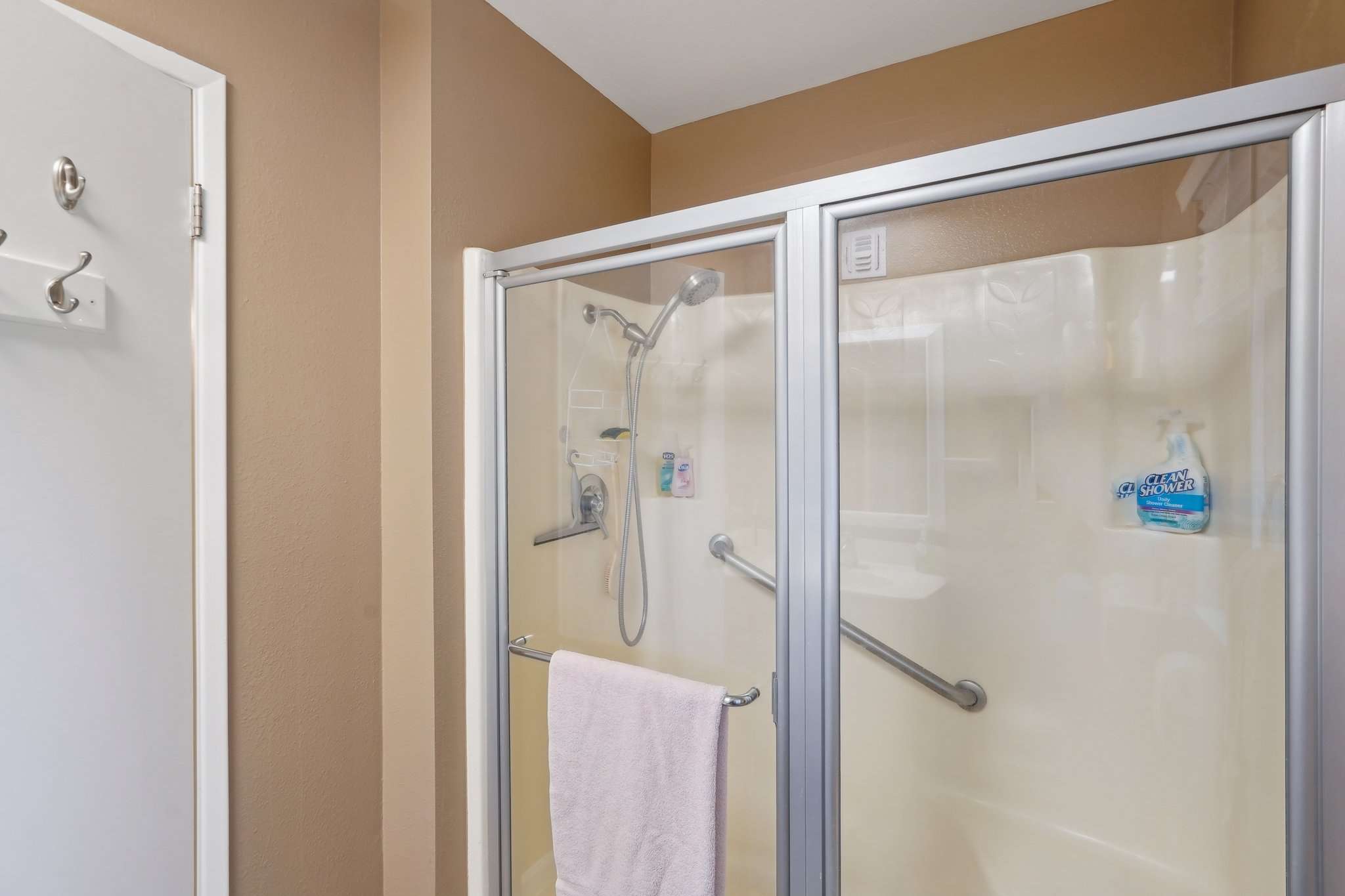 26 of 41. The spacious walk-in shower includes glass doors and built-in grab bars for safety and convenience. A thoughtful design for comfort and accessibility.