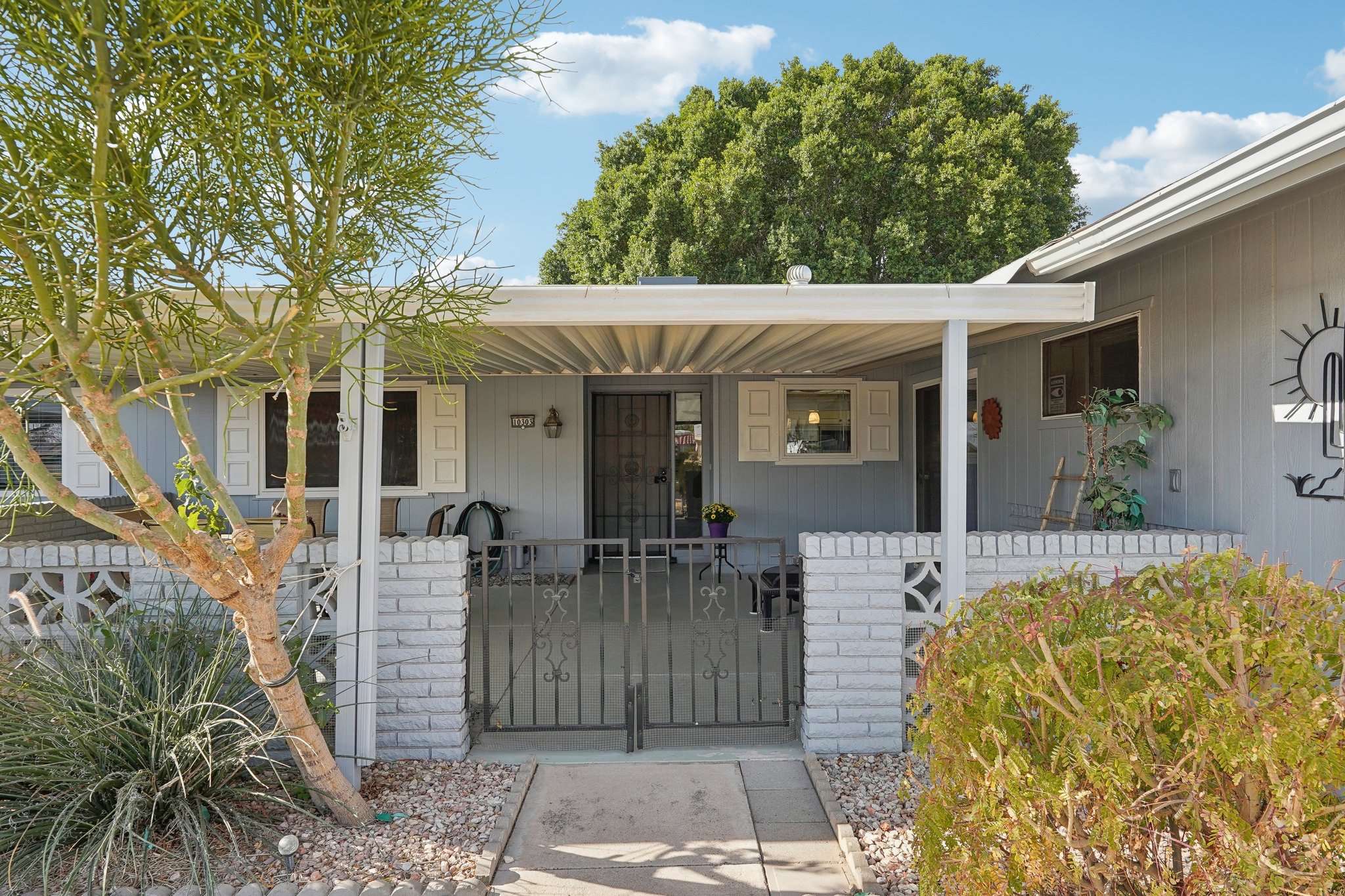 31 of 41. The front courtyard offers privacy and curb appeal, featuring a decorative gate, mature landscaping, and a covered patio, making for a welcoming entrance.