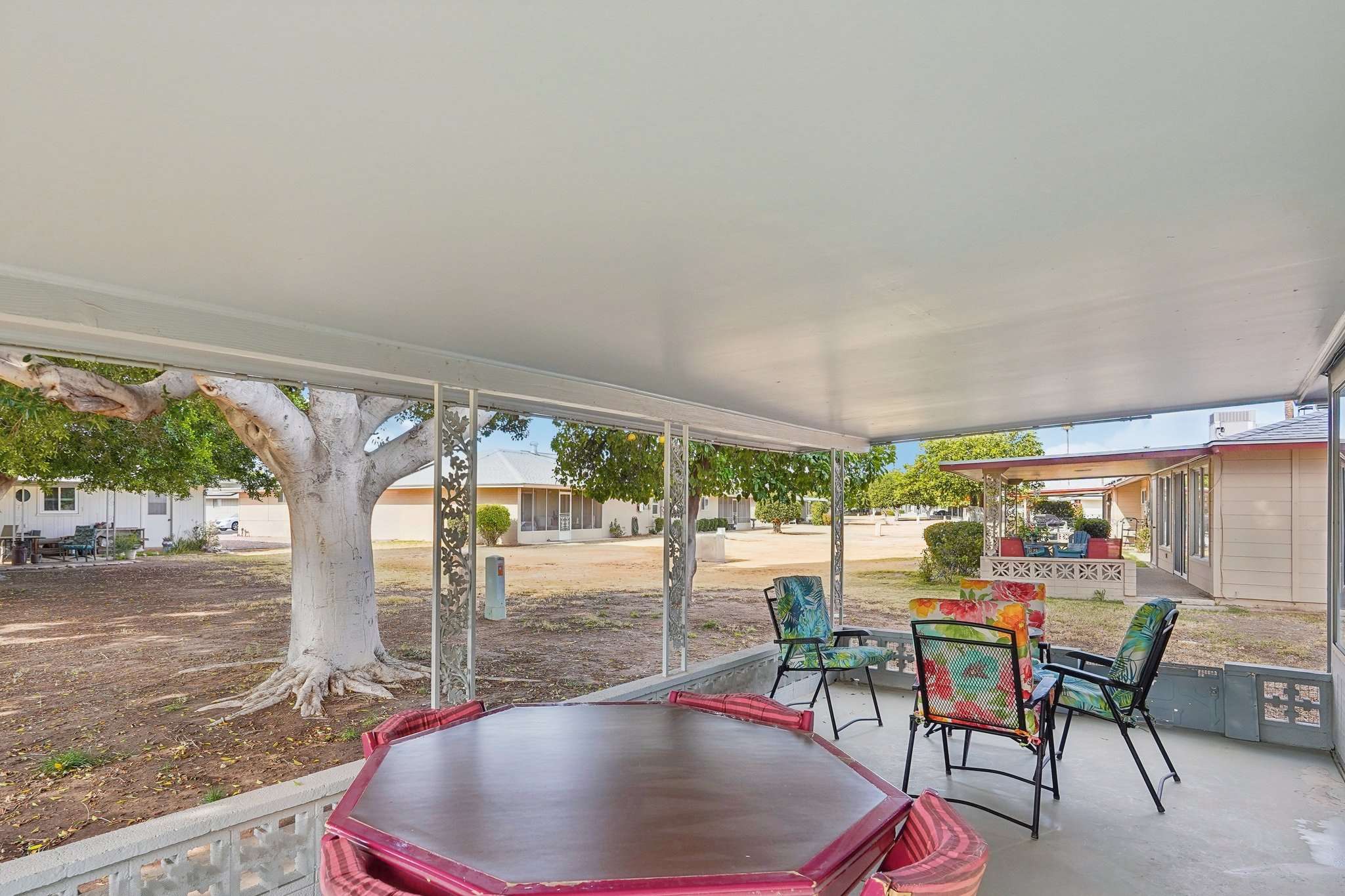 34 of 41. A large, covered back patio offers a peaceful retreat for outdoor dining and relaxation, overlooking an open community space with mature shade trees.