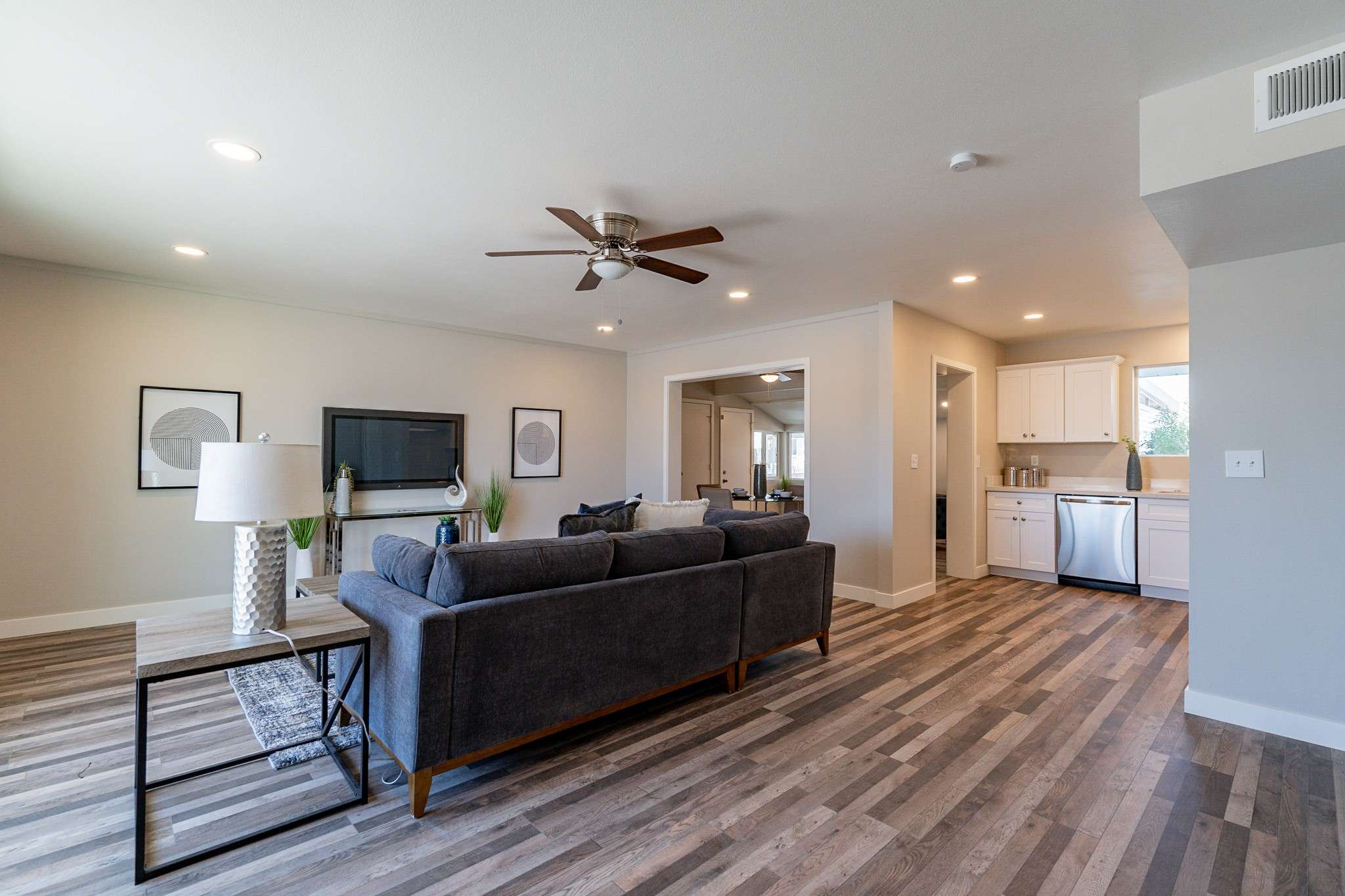 6 of 35. A bright and open living space featuring recessed lighting, wood-look laminate flooring, and a ceiling fan. Ideal for entertaining in a comfortable and stylish setting.
