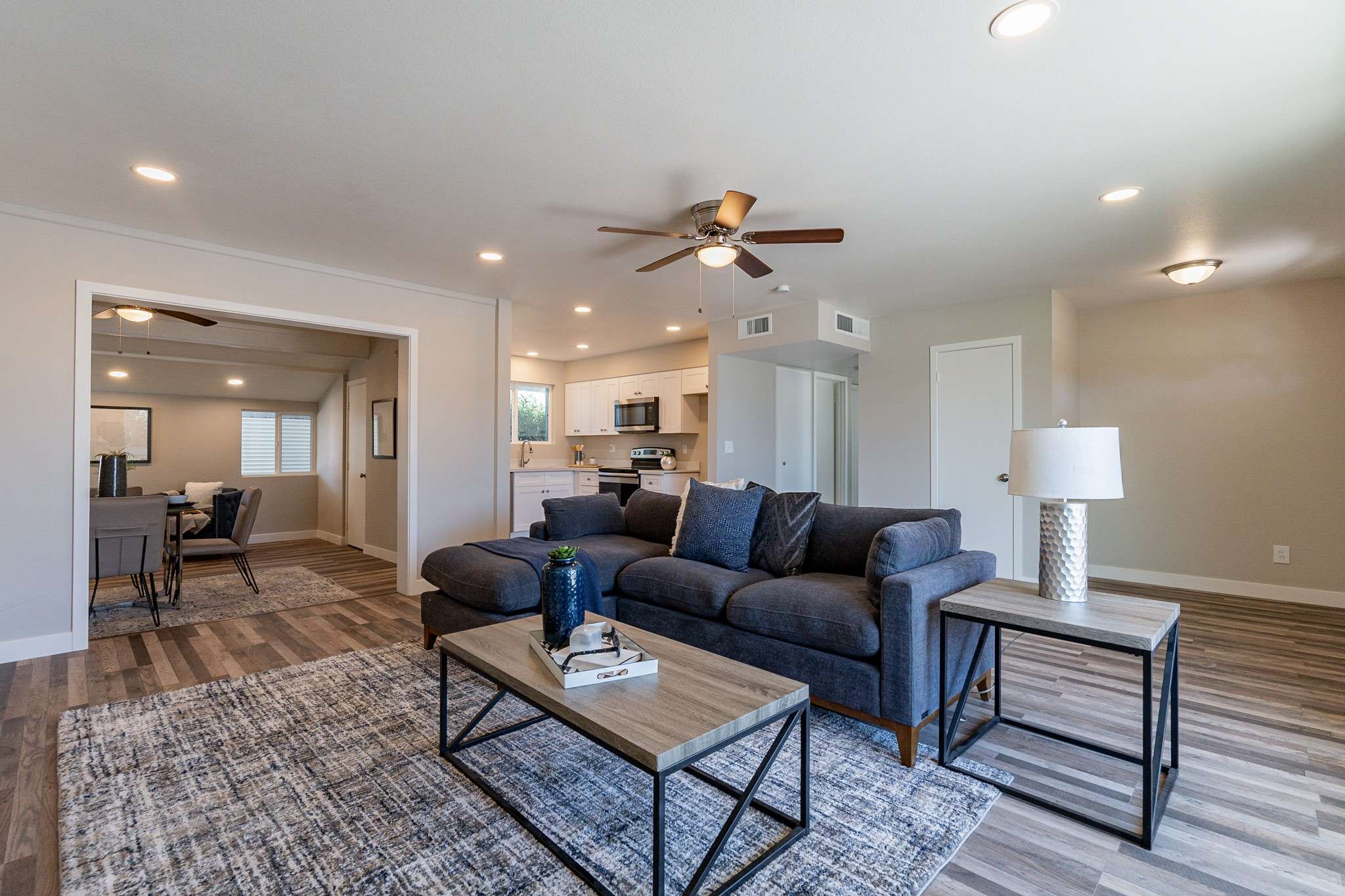 11 of 35. A spacious and inviting living area featuring modern recessed lighting, neutral tones, and stylish laminate flooring. The seamless open floor plan is perfect for relaxation or entertaining guests.