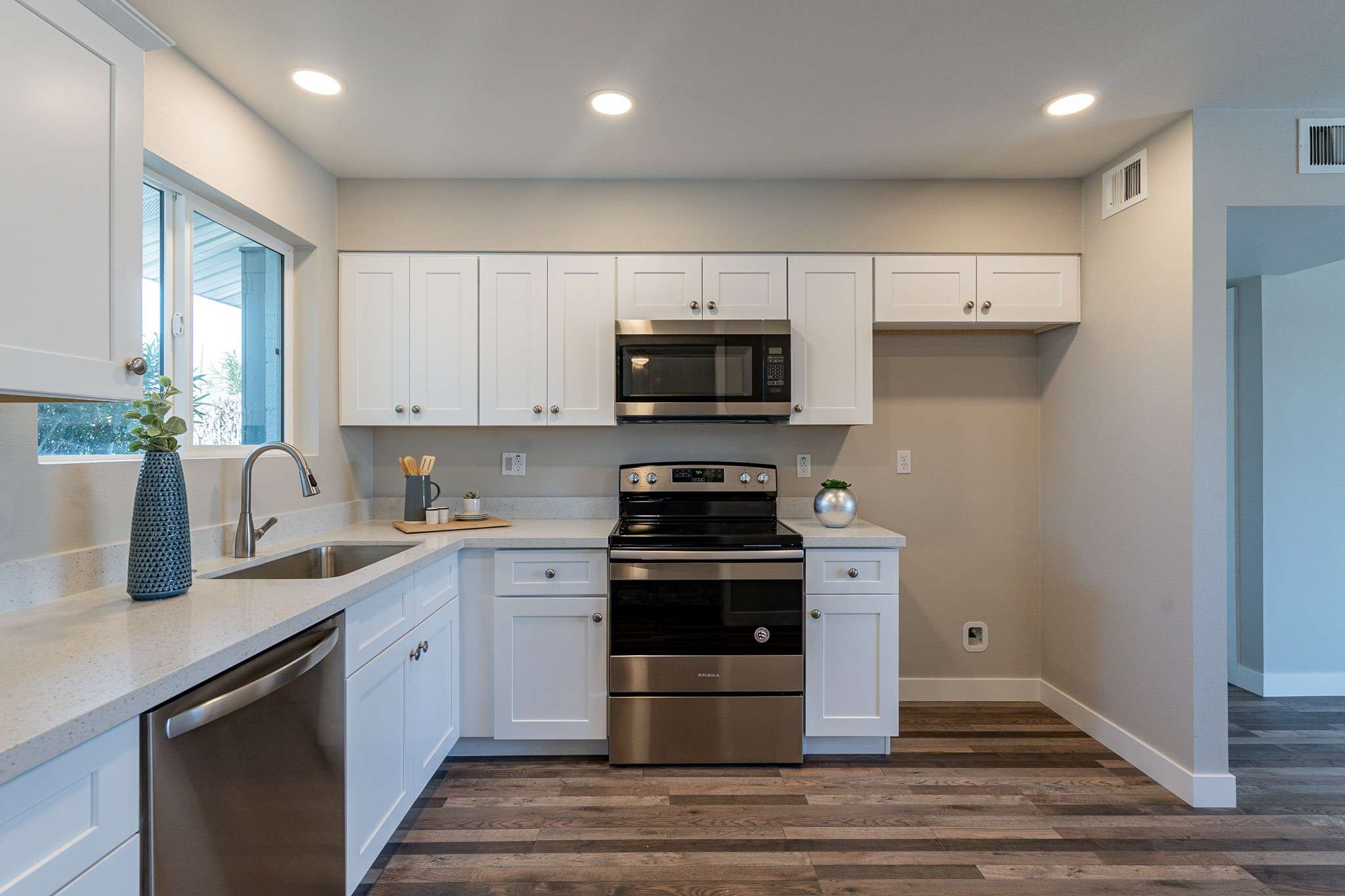 16 of 35. A chef s dream kitchen featuring quartz countertops, stainless steel appliances, and sleek white cabinetry. The open design creates a bright, stylish cooking space.