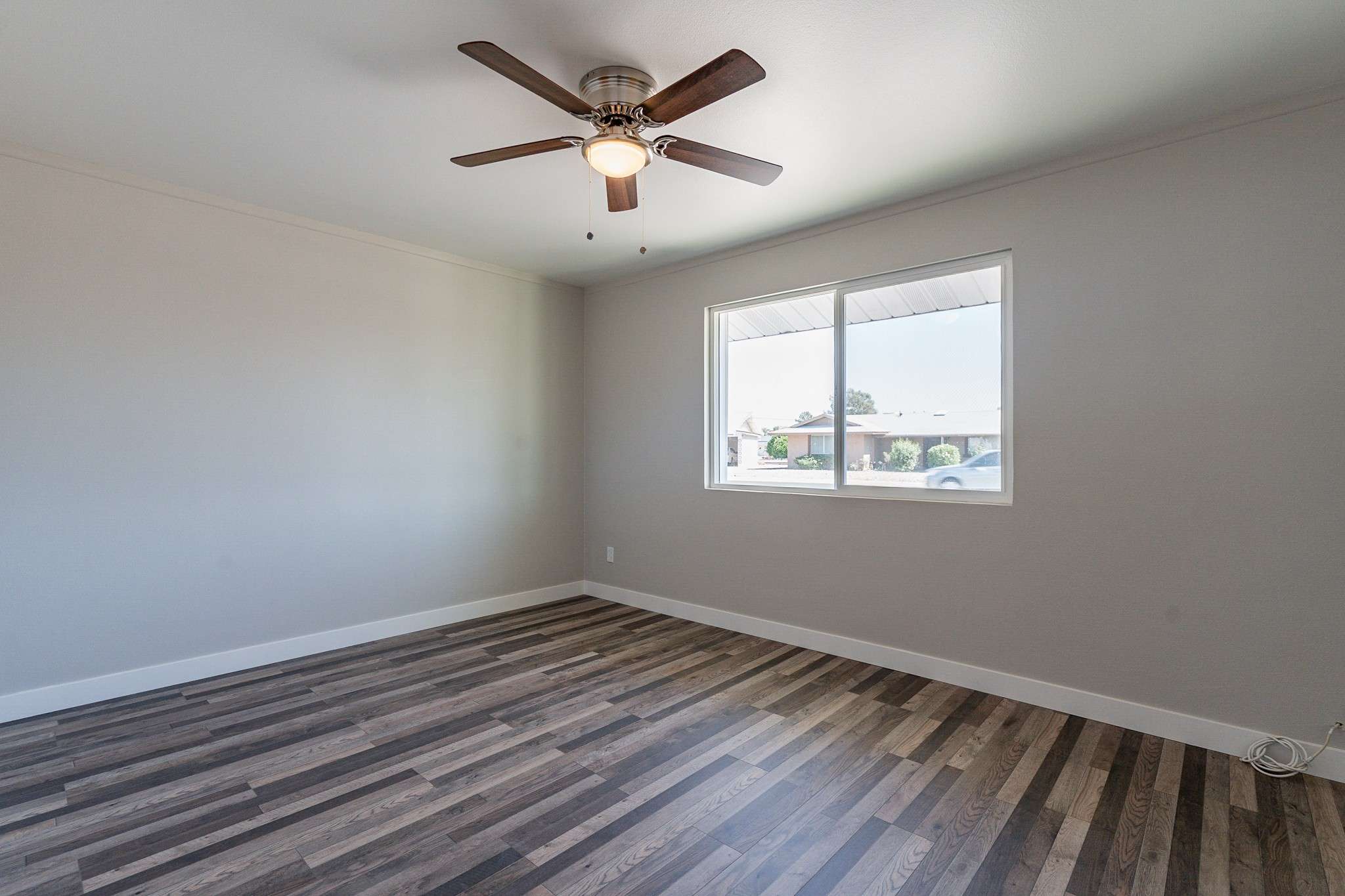 21 of 35. This inviting bedroom features large windows for natural light, modern wood-look flooring, and a ceiling fan for comfort. A perfect space for rest and relaxation.