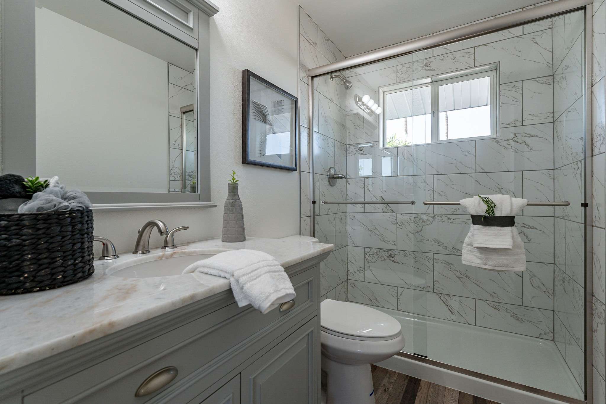 25 of 35. A spa-like bathroom featuring a glass-enclosed shower with marble-style tile, a chic vanity, and updated fixtures. The perfect combination of luxury and functionality.