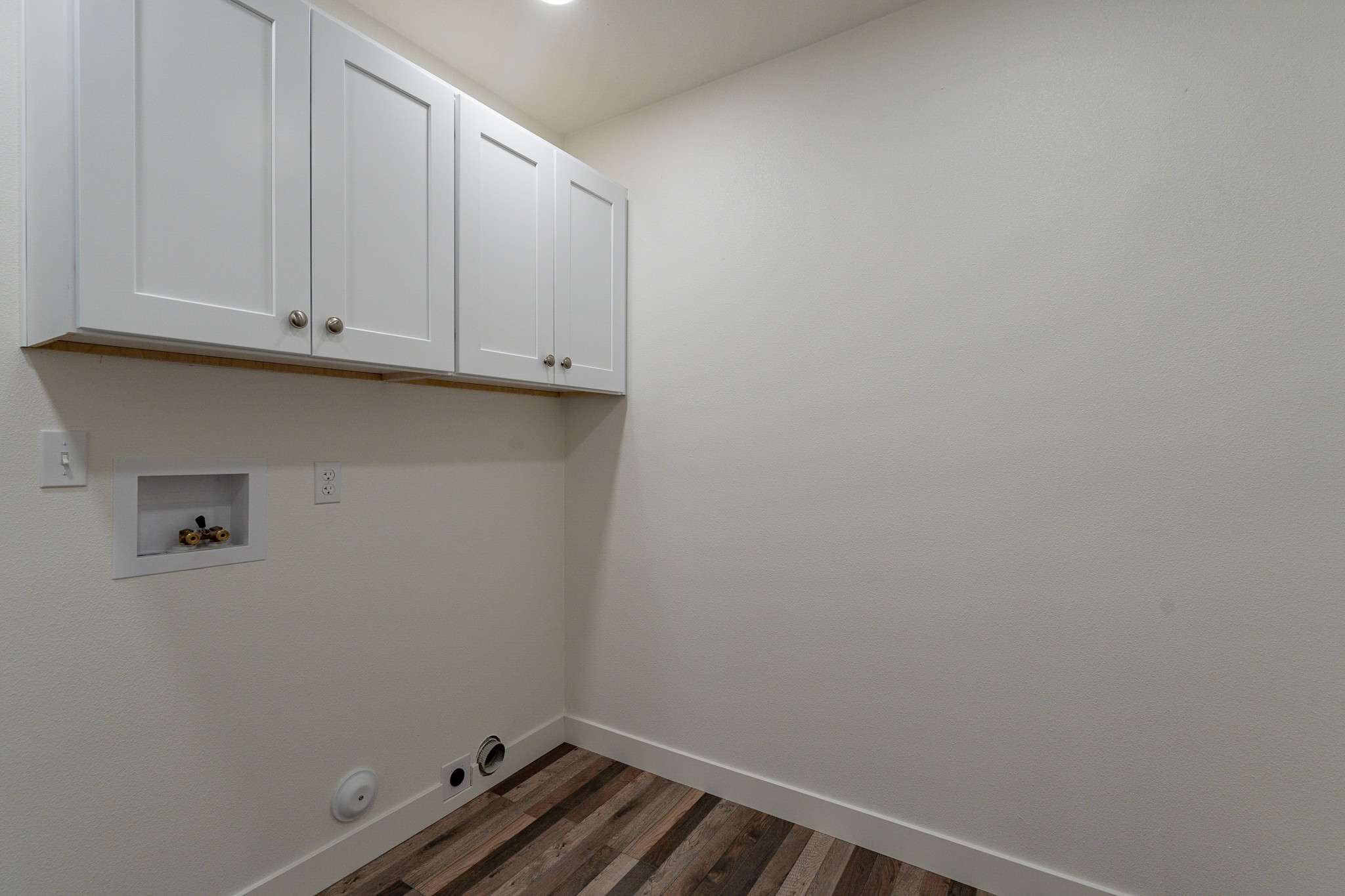 26 of 35. A well-organized laundry space equipped with built-in upper cabinets for extra storage. Bright lighting enhances convenience in this essential home feature.