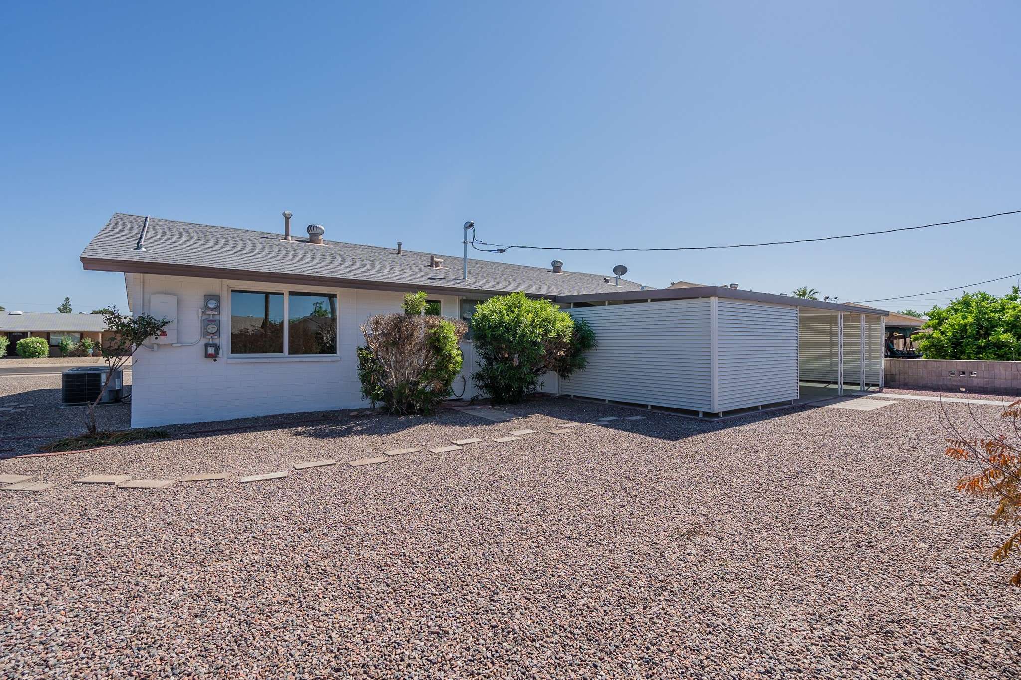 32 of 35. Enjoy the tranquility of this beautifully landscaped backyard, featuring vibrant greenery and a shaded patio area. Designed for relaxation and minimal upkeep, this space is perfect for year-round outdoor enjoyment in a sunny climate.