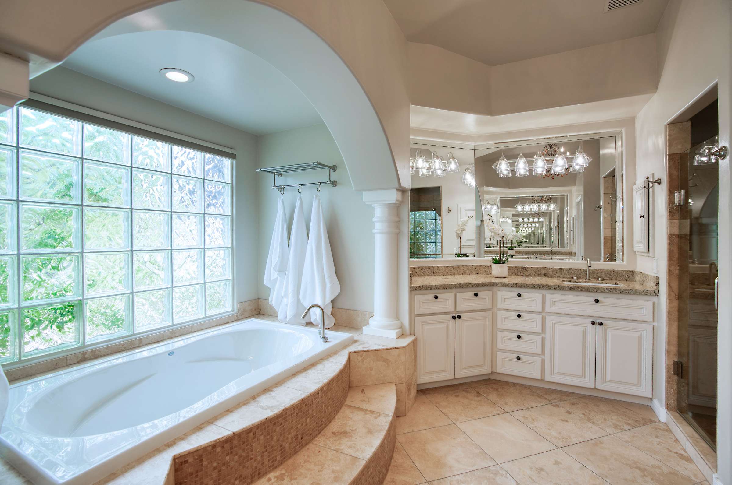 17 of 65. This refined bathroom includes two expansive vanities, a walk-in shower, and stunning tilework under a tray ceiling all wrapped in a soft, spa-inspired color palette.