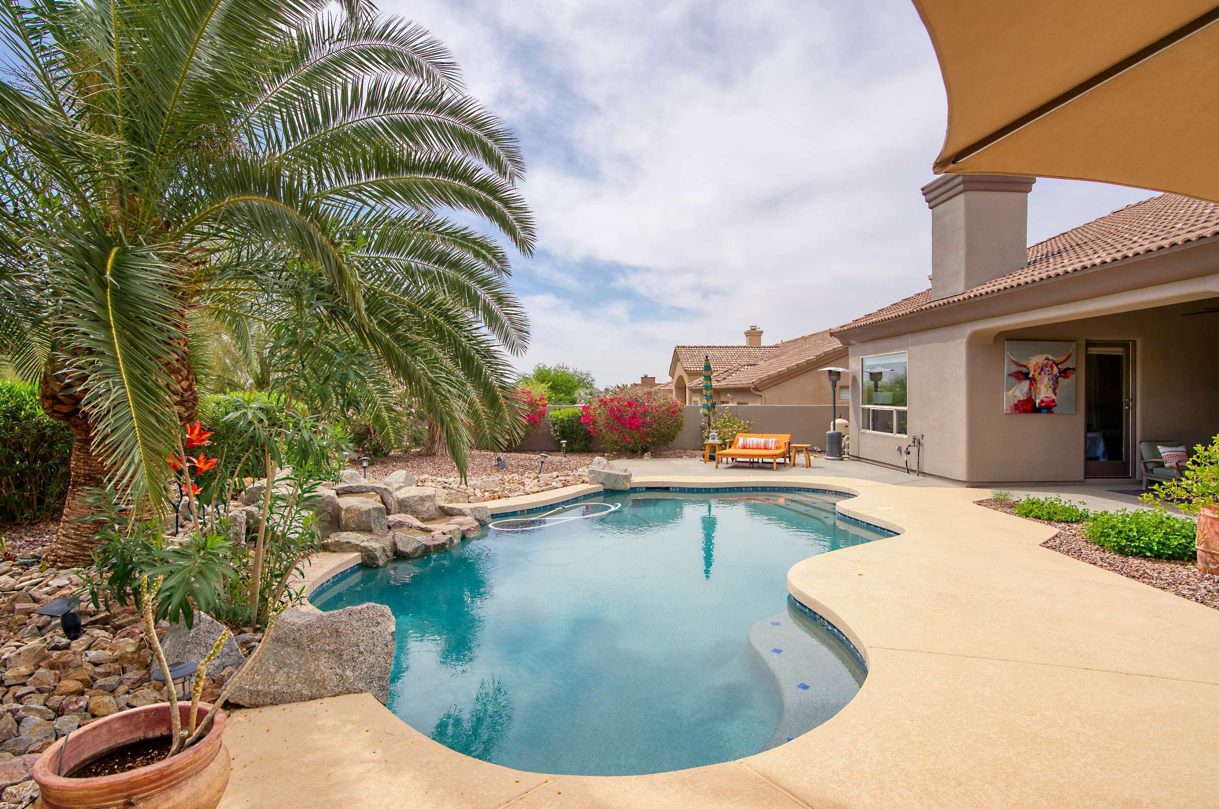 31 of 65. Discover a serene backyard setting with lush green space, mature trees, and privacy landscaping. This versatile outdoor area is ideal for family fun, pets, or future customization in sunny Arizona.